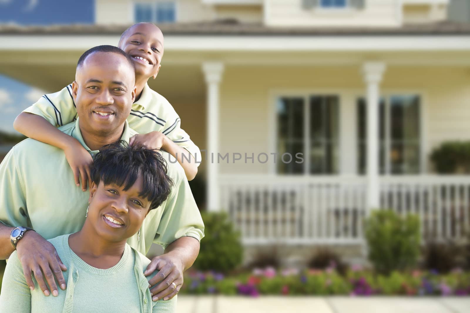 Happy Attractive African American Family in Front of Beautiful House.