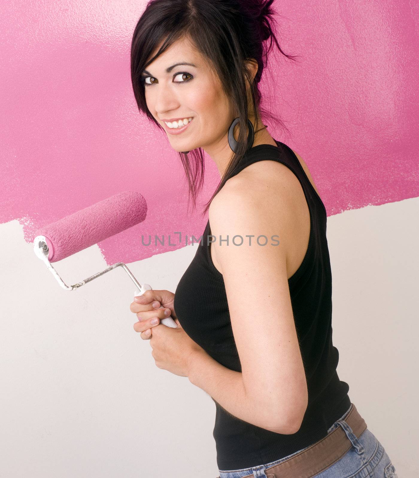 A brunette woman paints the wall of her apartment