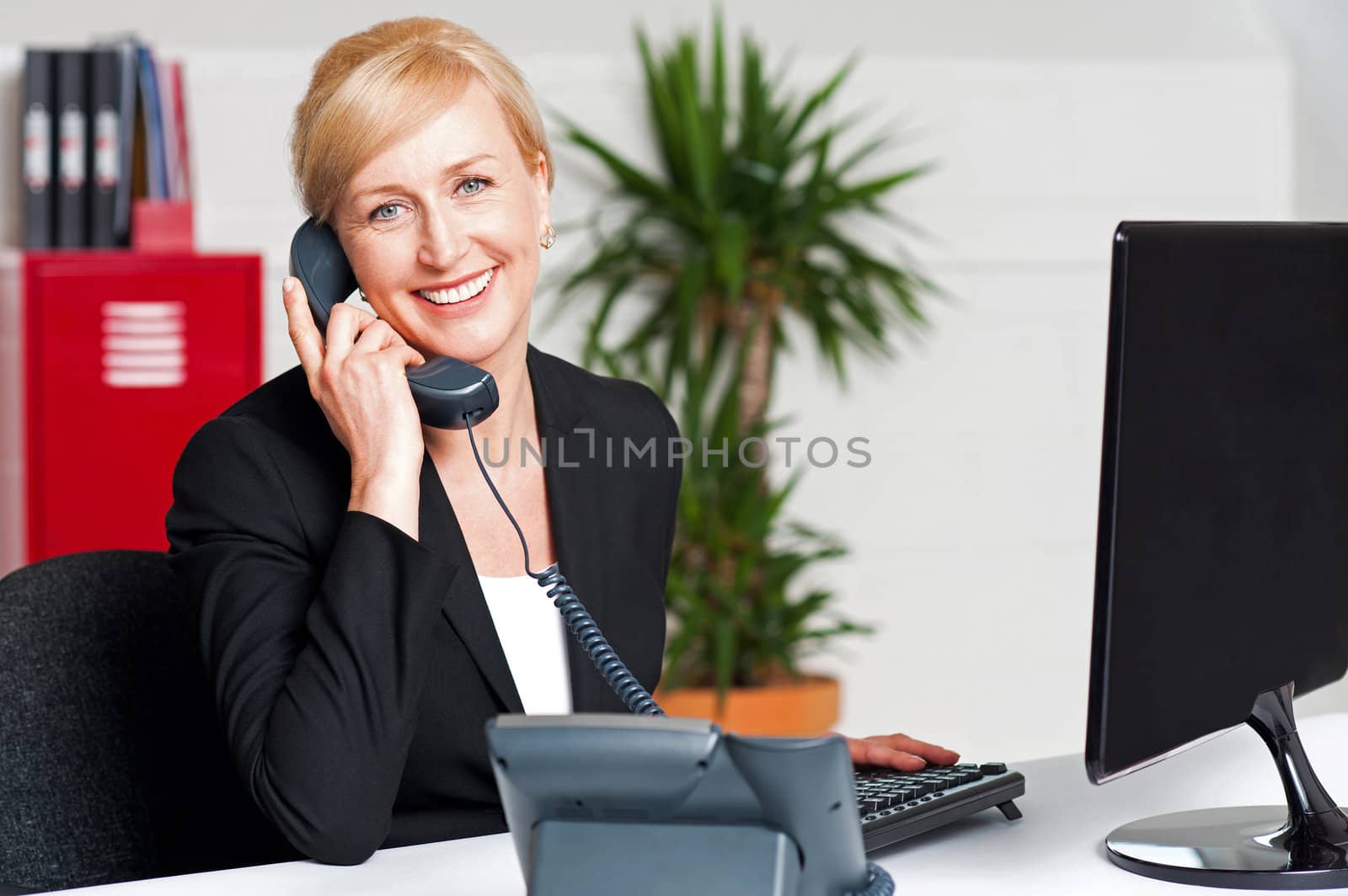 Secretary talking on phone with client, looking at you