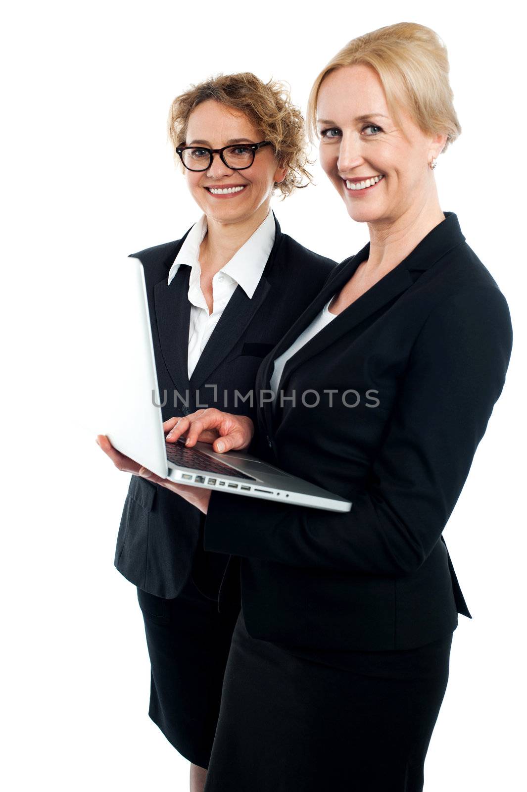 Side view portrait of two corporate women working on laptop isolated against white background