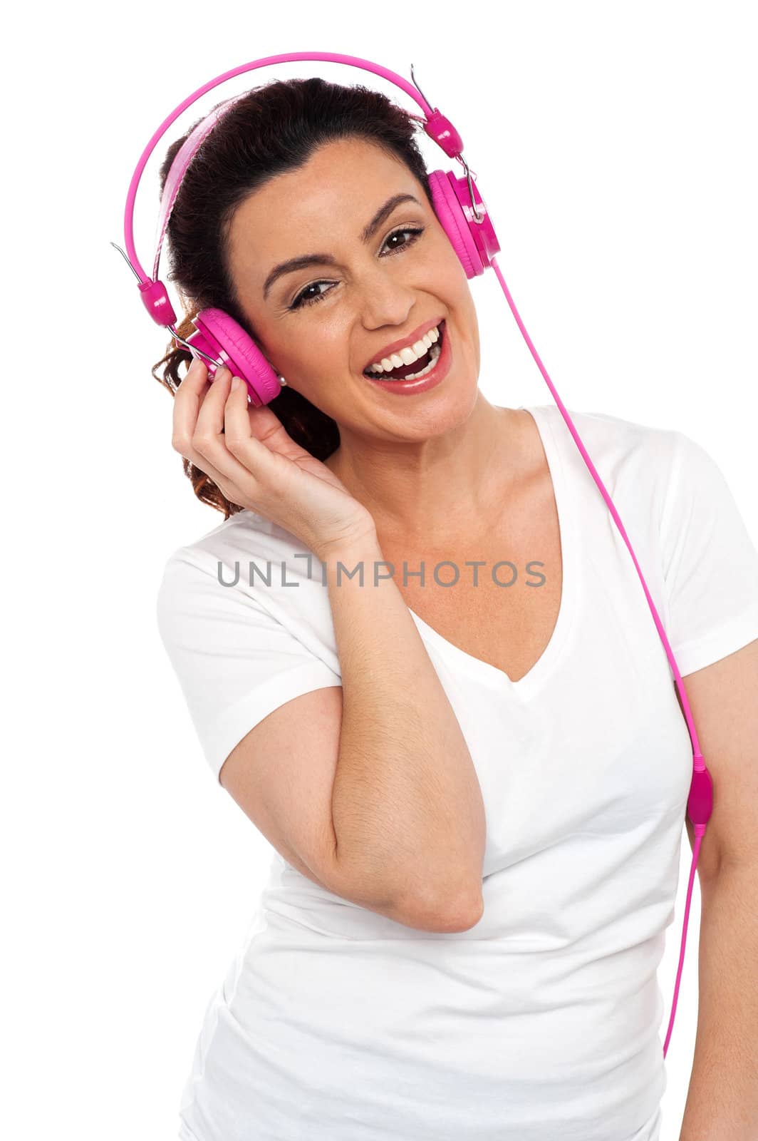 Profile shot of a cheerful young beautiful lady enjoying music on her pink headphones