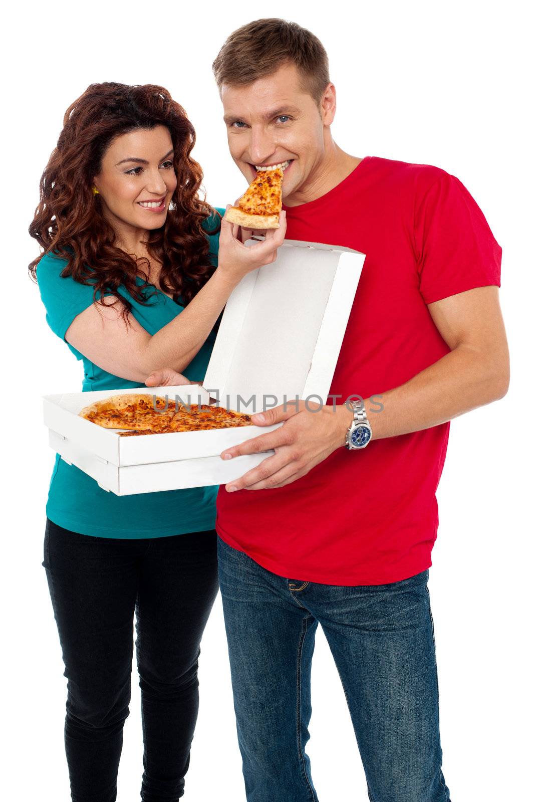 Caring girlfriend making her boyfriend eat pizza. Adorable love couple