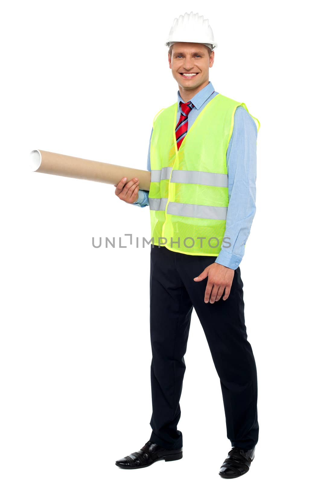 Smiling young architect holding blueprints, wearing helmet and safety jacket