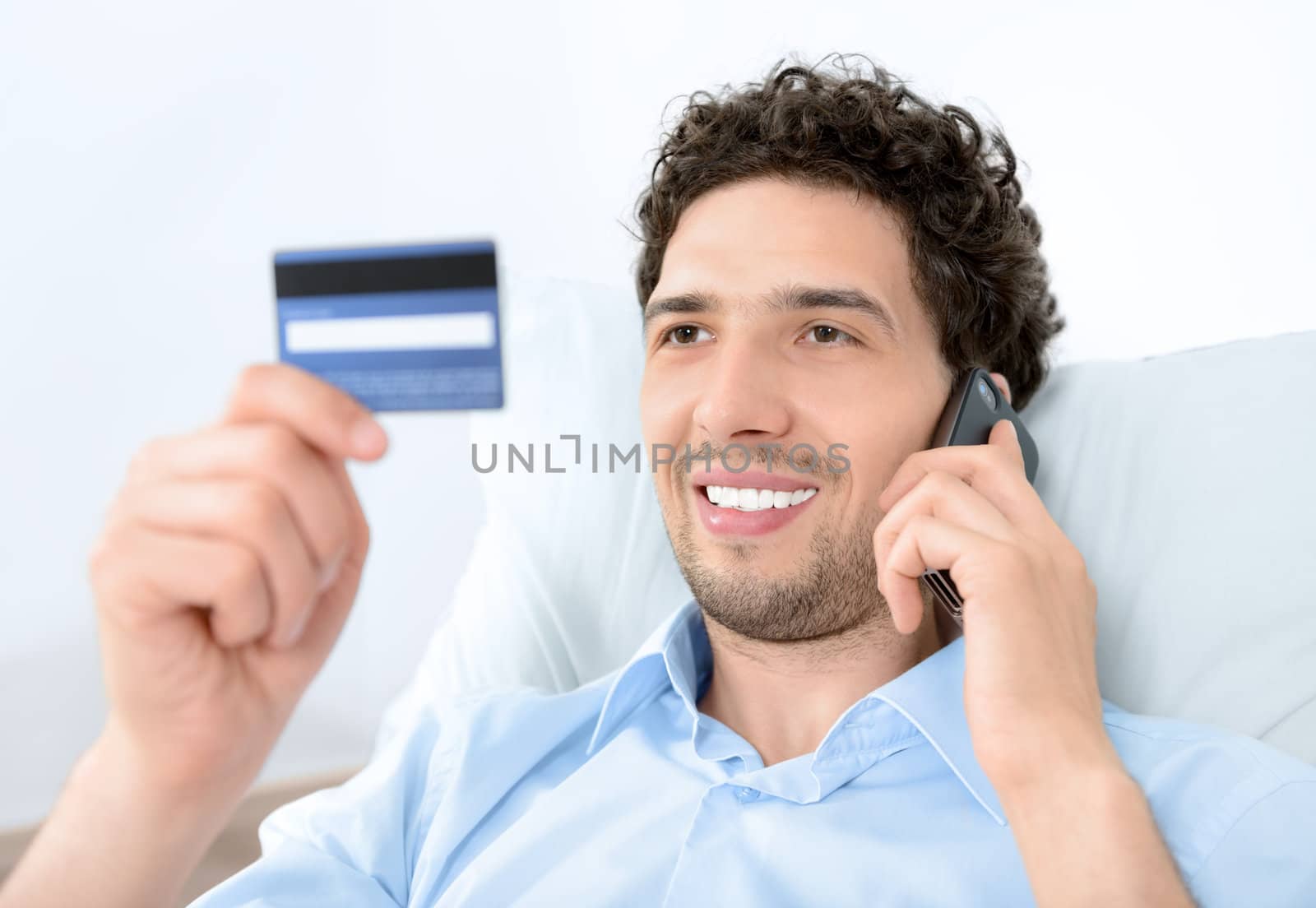 Young man on mobile with credit card by bloomua