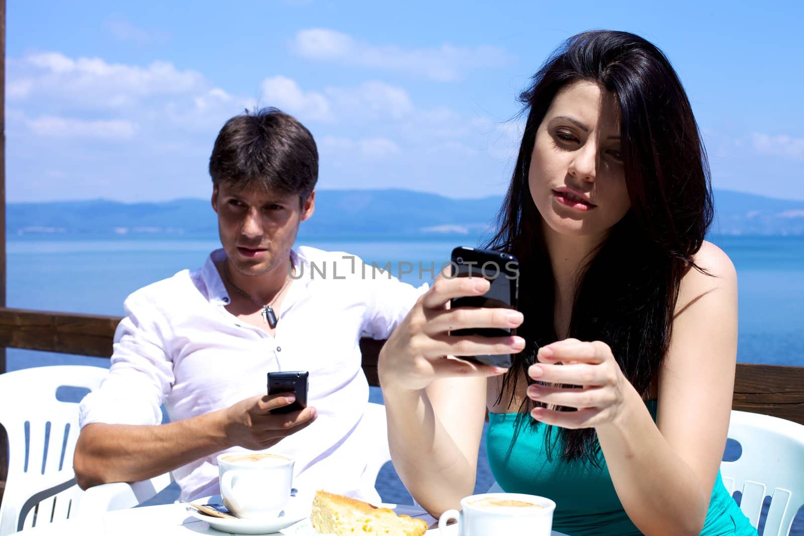 Couple texting with cellphones on a lake