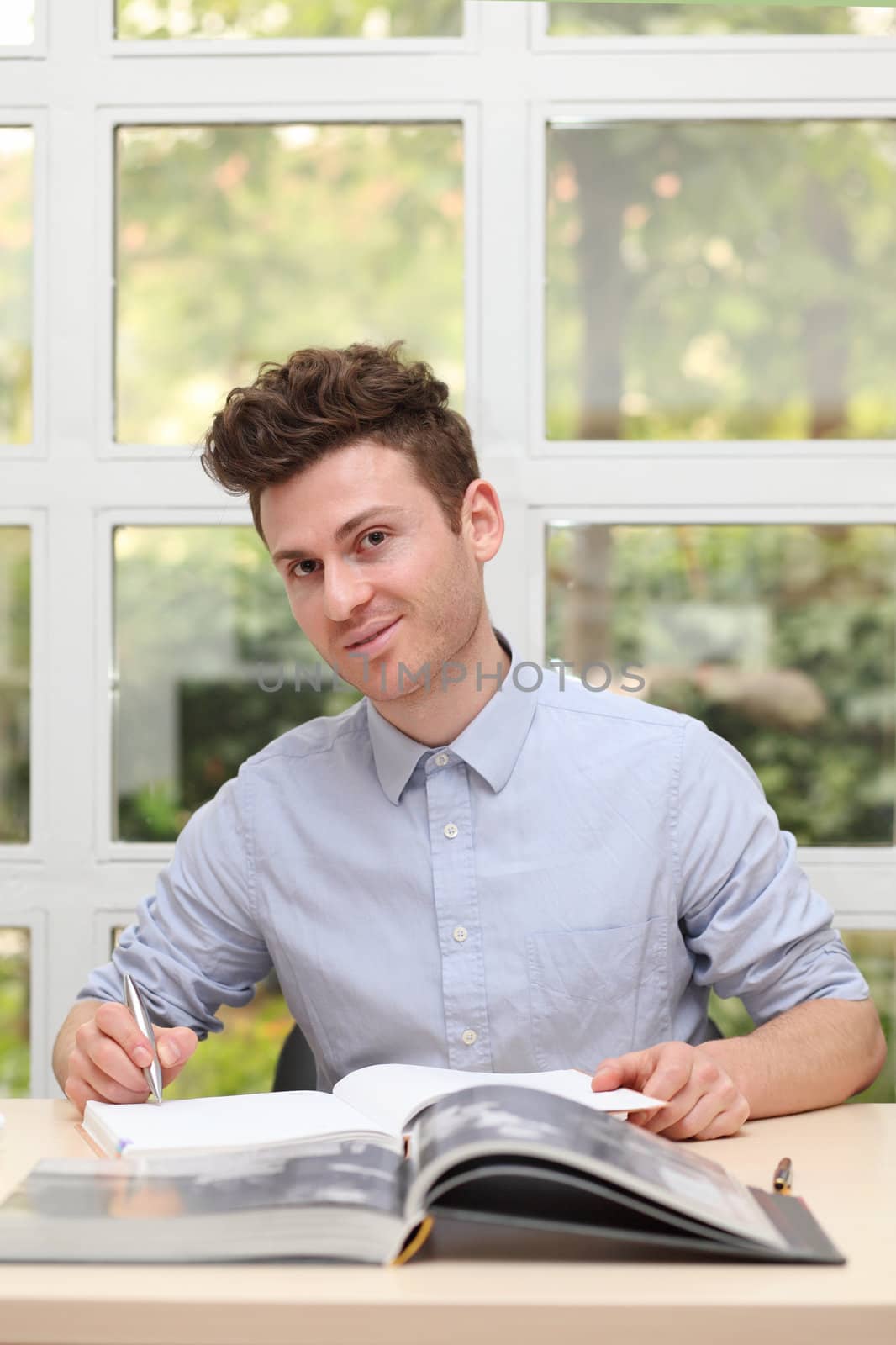 Young adult man writing notes with pen