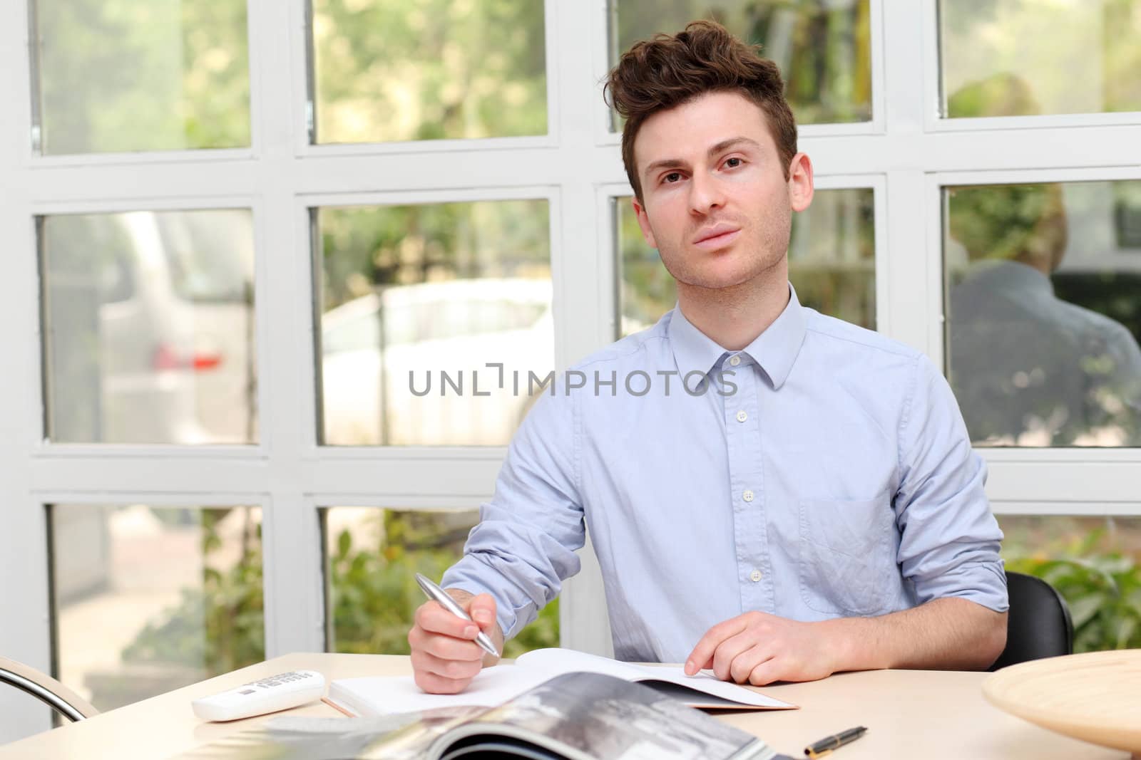 Young adult man writing notes with pen