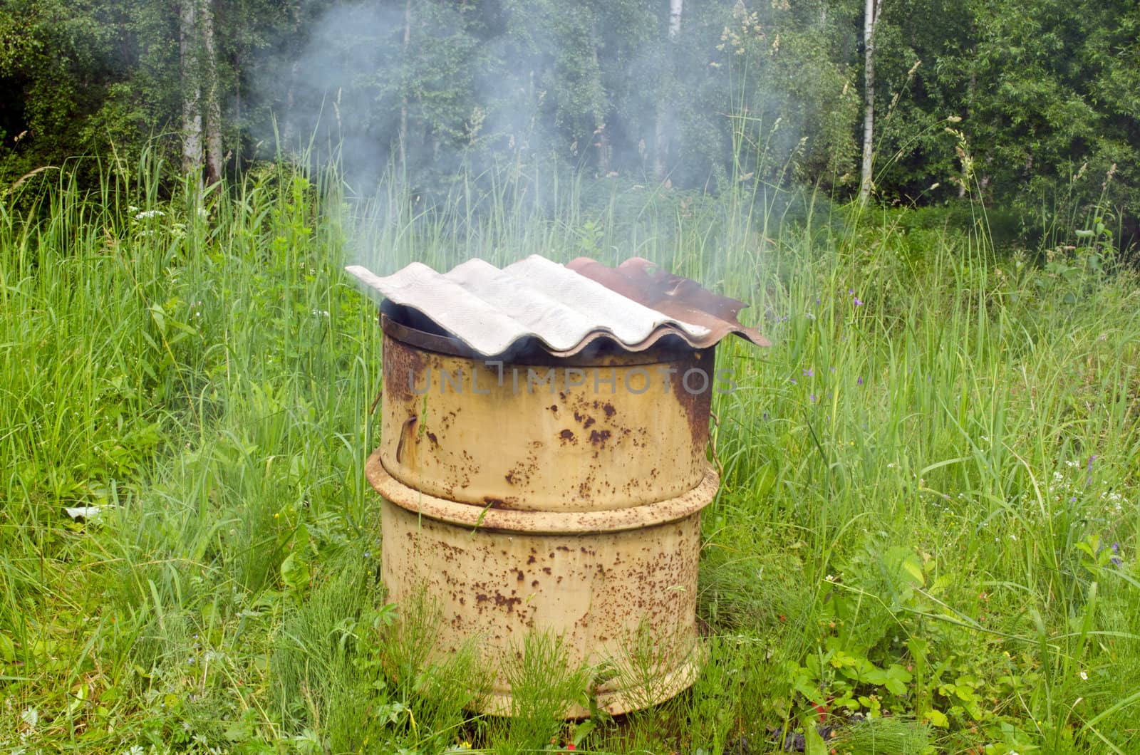 Smoke rises from old rural handmade barrel smokehouse asbestine slate roof.