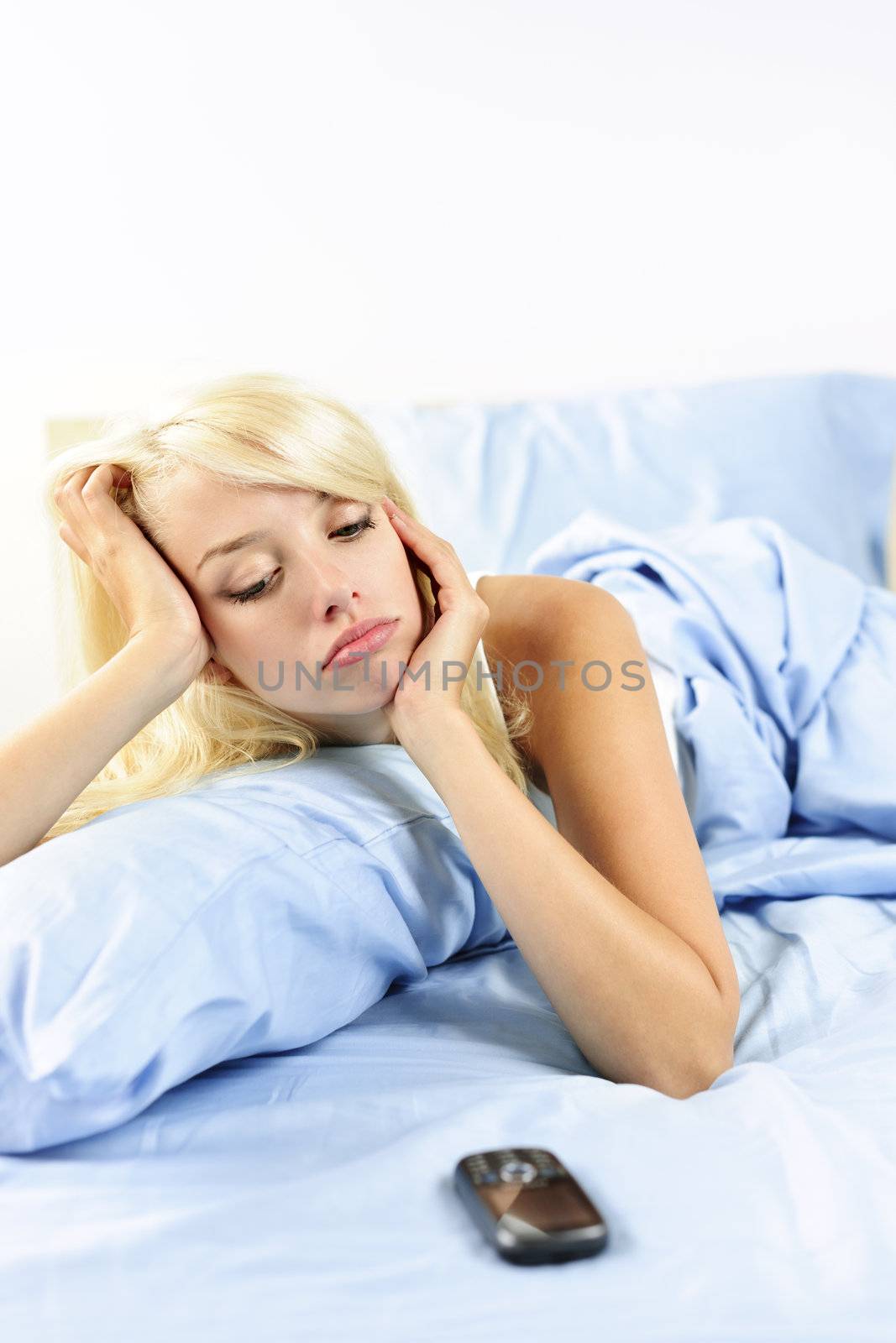 Lonely blonde woman waiting for phone call in bed at home