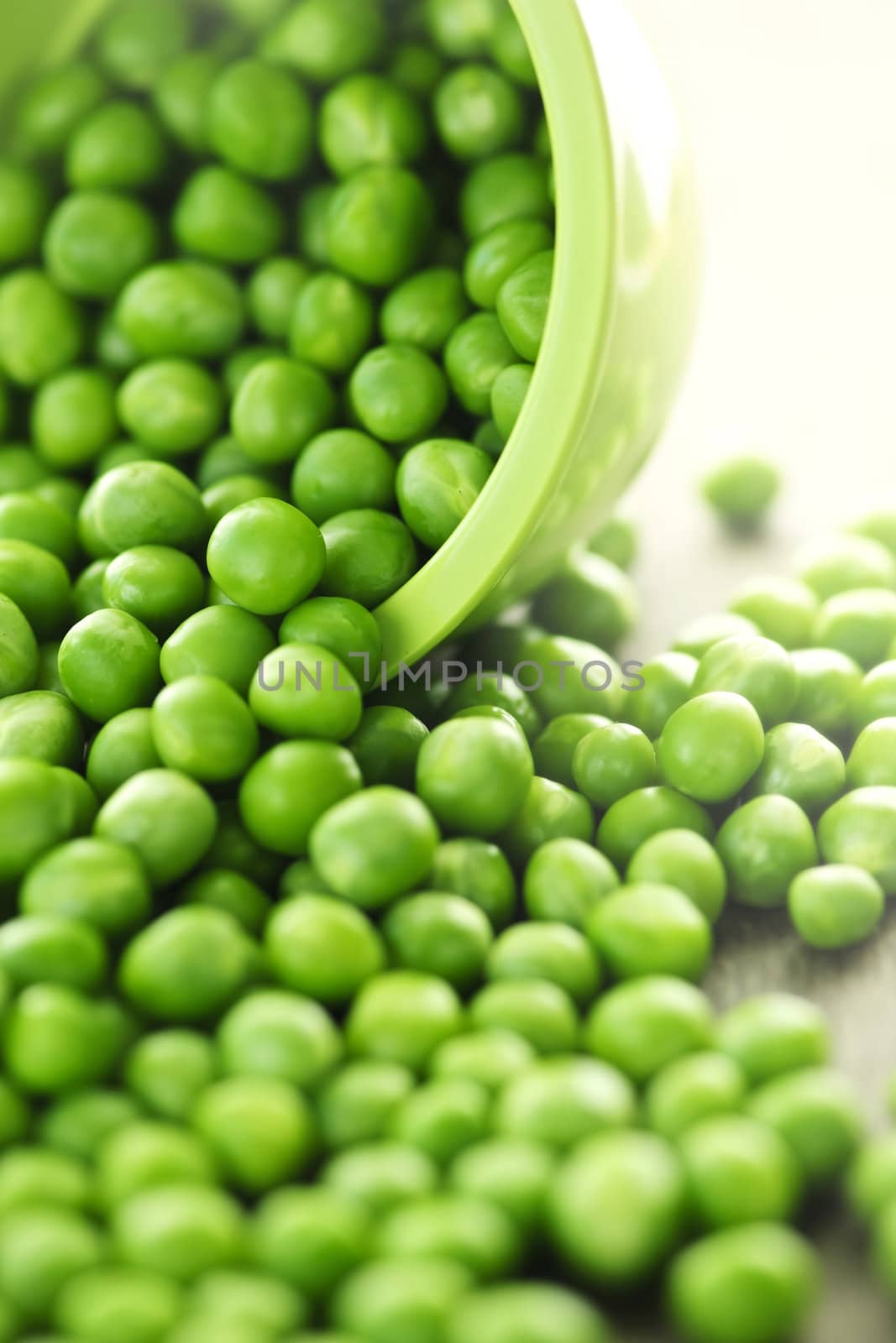 Closeup on spilling bowl of fresh green green peas