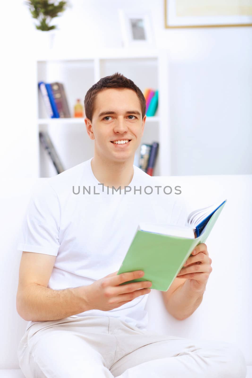 Young handsome man at home with a book