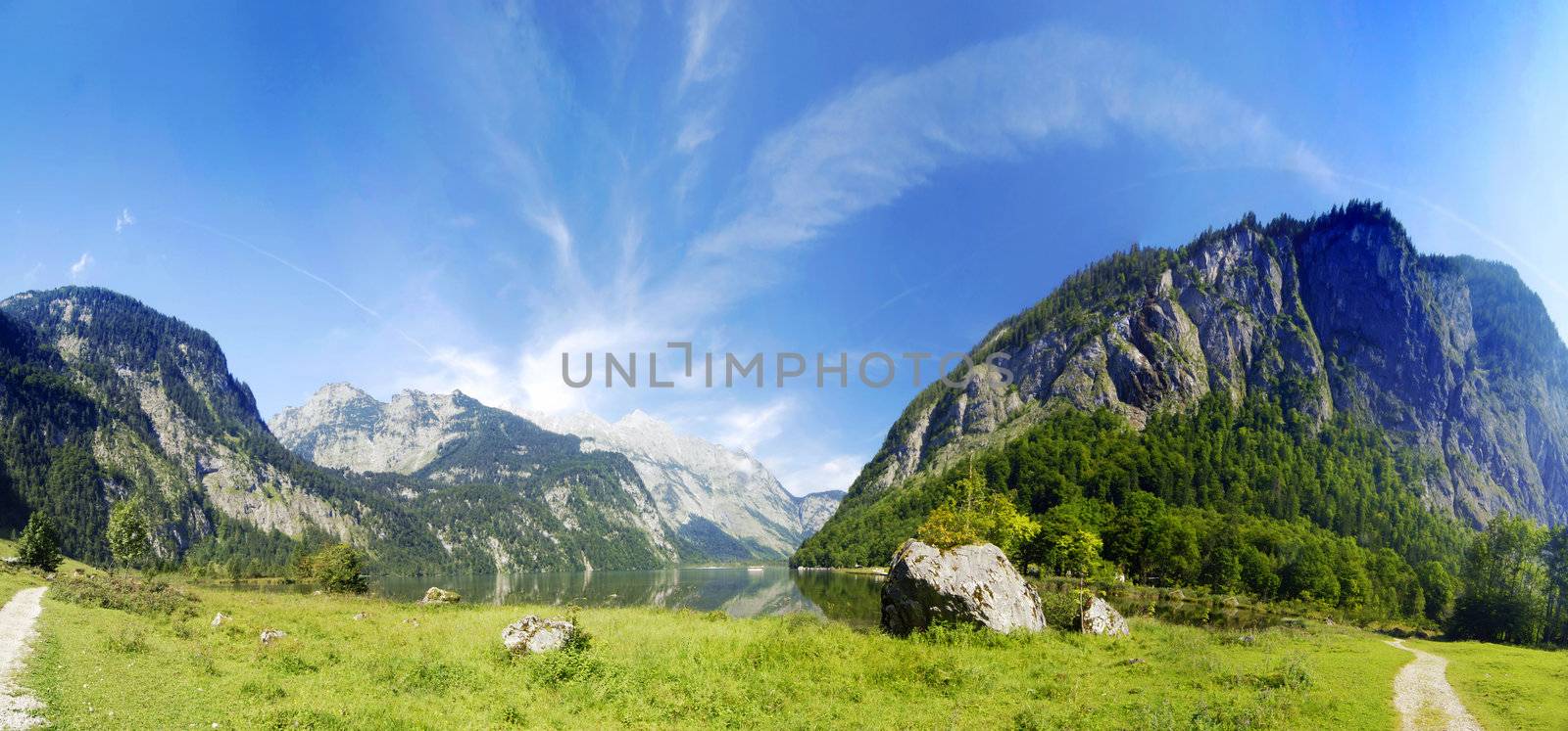 Alpine peaks with lake and green meadow in panoramic composition