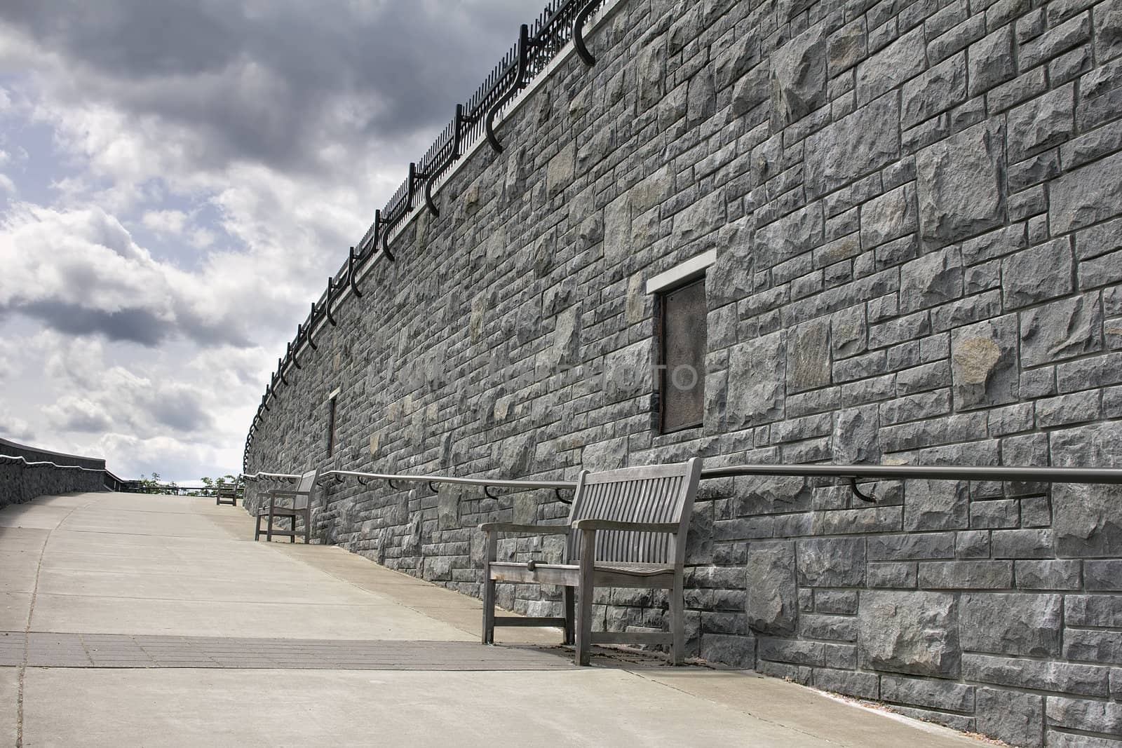 Wooden Benches Along Stone Rock Wall of Public Park Walkway