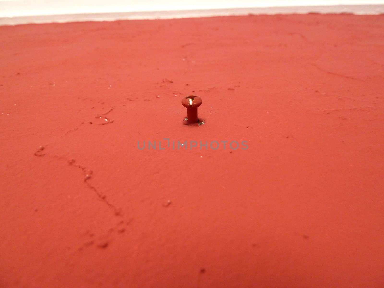 red painted surface with a single screwhead