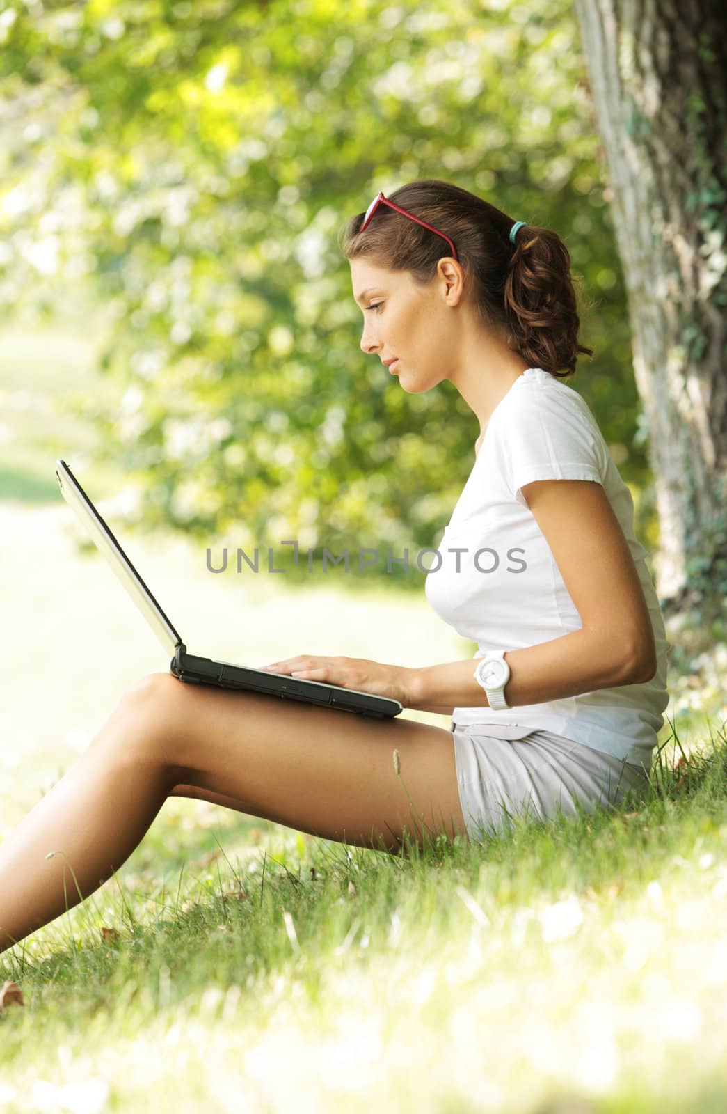 Young woman sitting on a  lawn using laptop