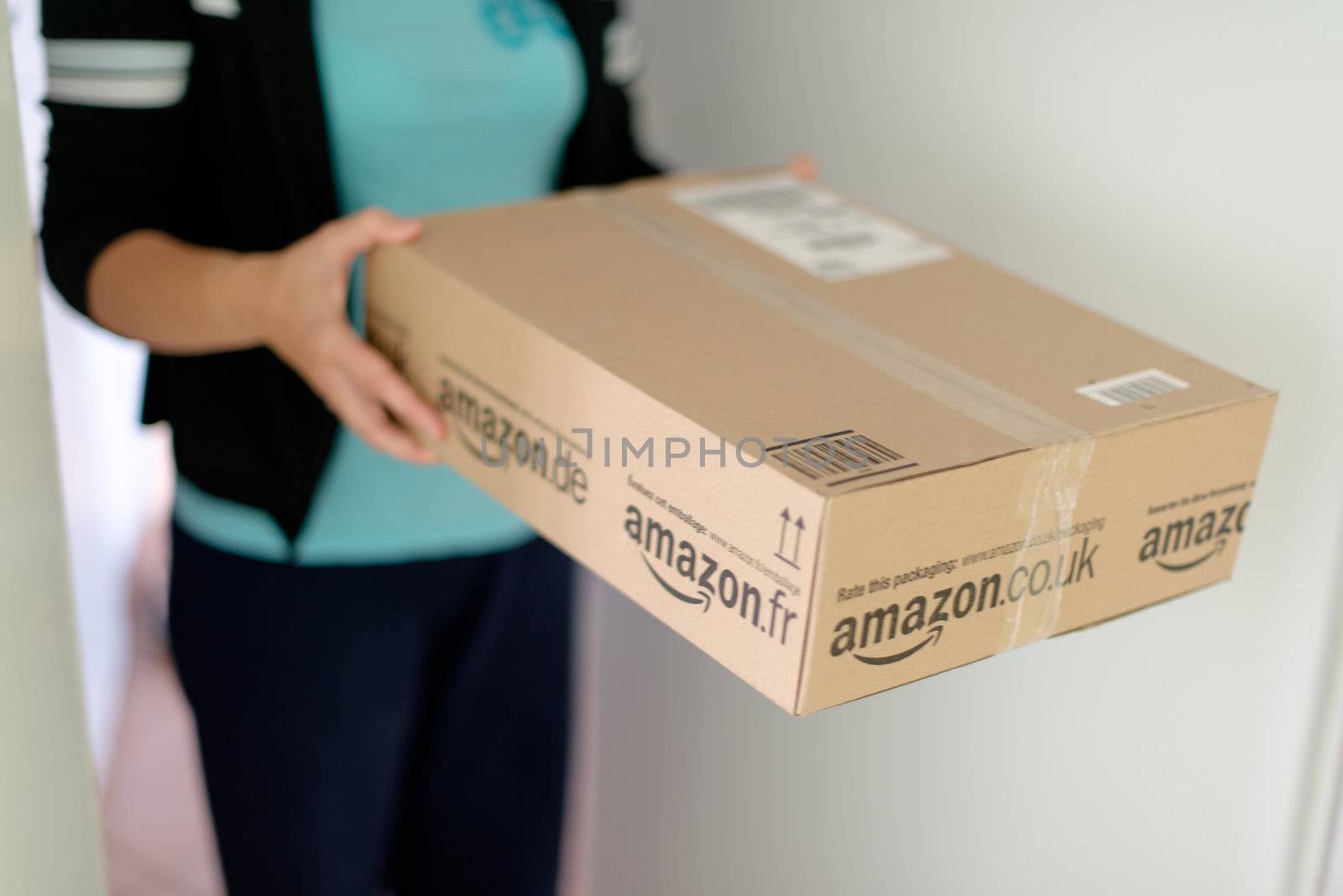 STUTTGART - SEPTEMBER 2: Woman picking up a parcel by Amazon.com in front of her flat on September 2, 2012 in Stuttgart, Germany. Amazon.com is delivering thousands of parcels every day to German households.