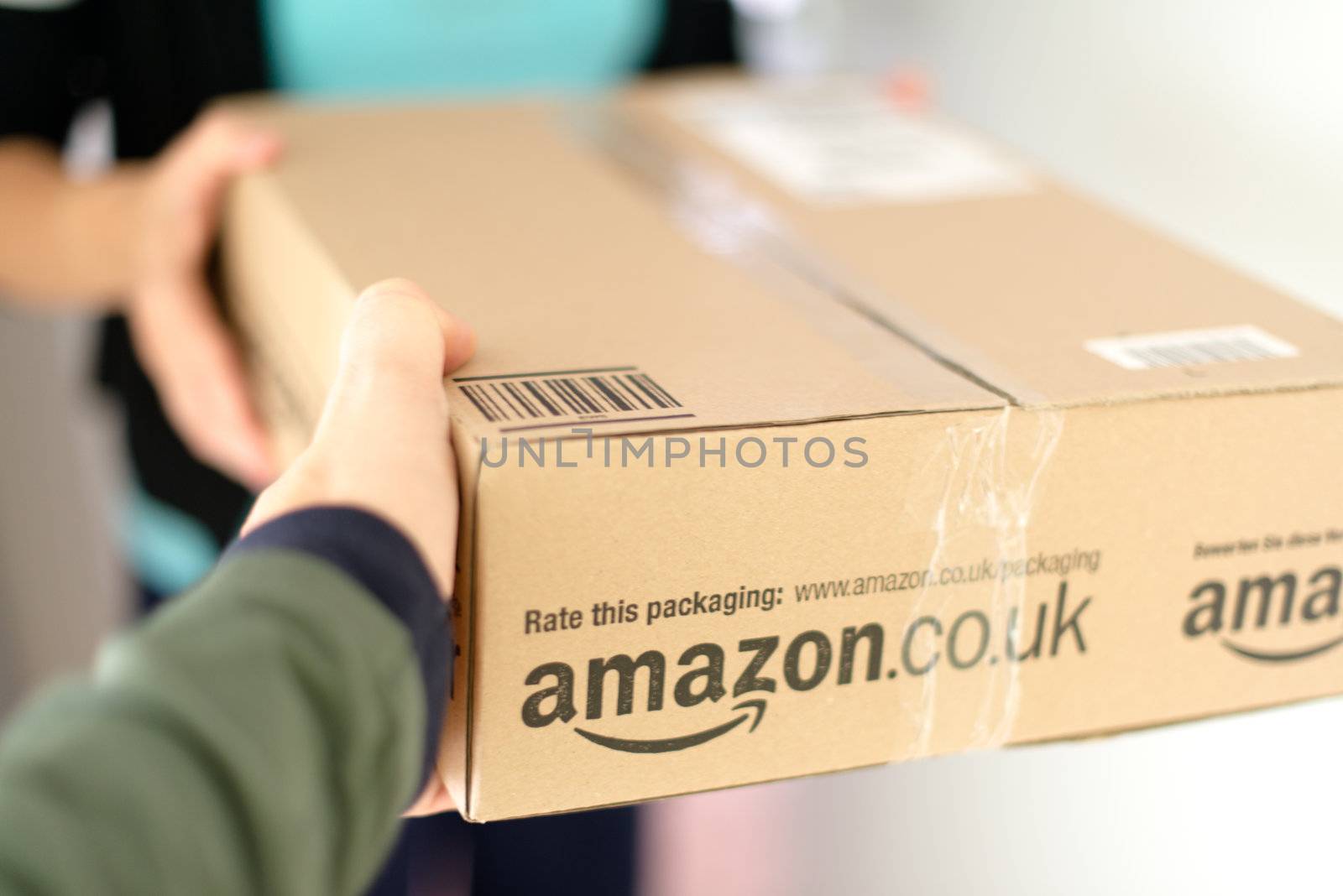STUTTGART - SEPTEMBER 2: Woman receiving a parcel by Amazon.com delivered by the mailman in front of her flat on September 2, 2012 in Stuttgart, Germany. Amazon.com is delivering thousands of parcels every day to German households.