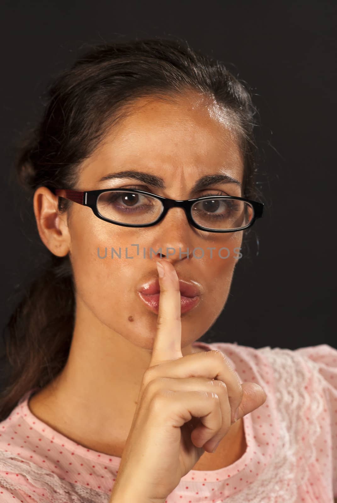 Serious looking woman in glasses requesting silence