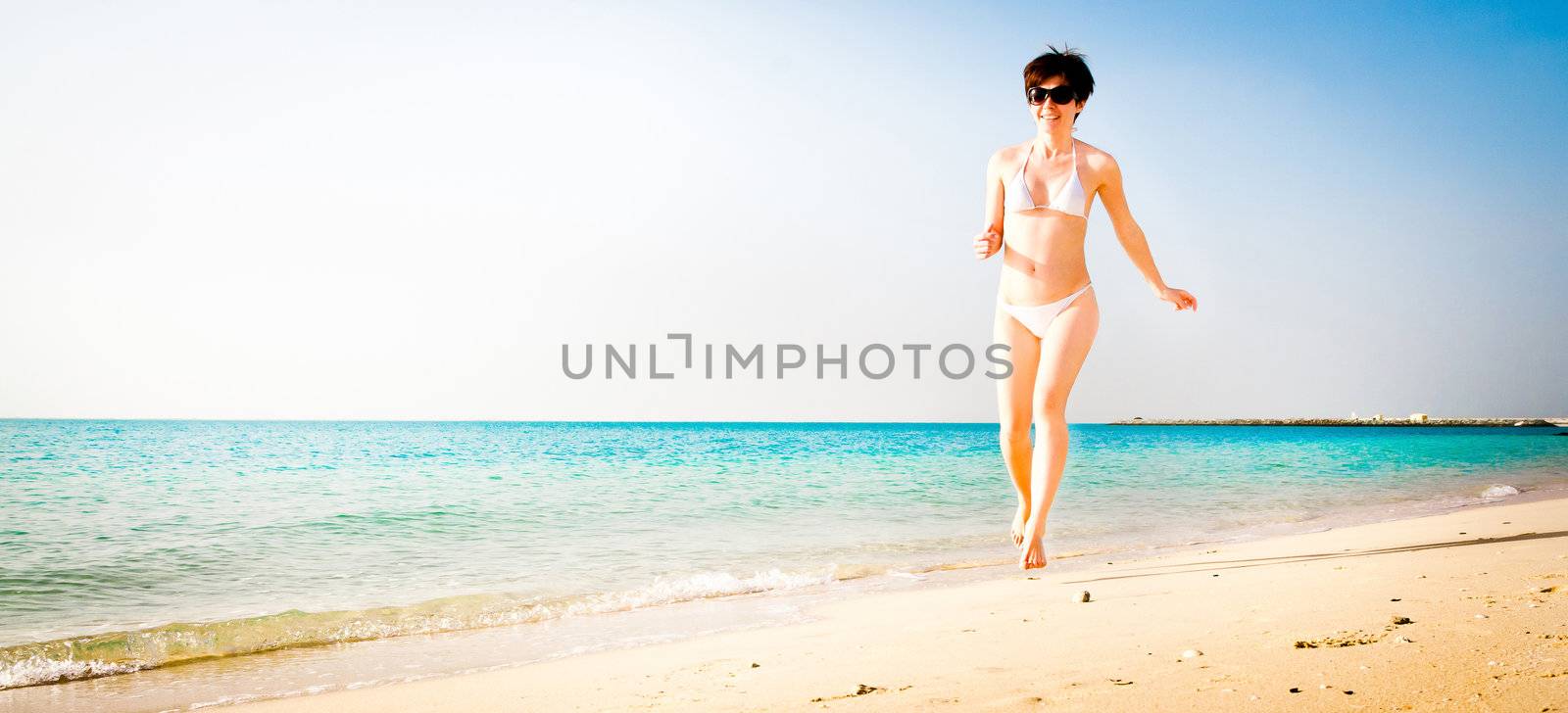 beautiful girl in a white bikini running on the beach