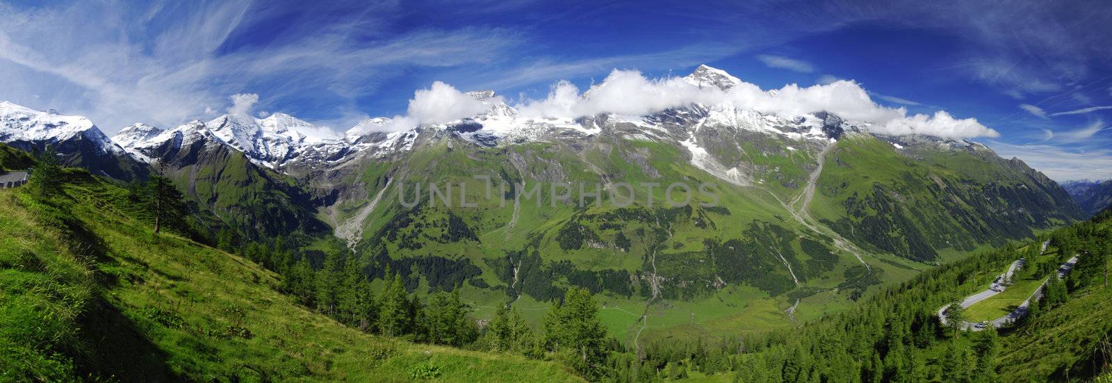 Beautiful alpine landscape with peaks covered by snow are lost in clouds