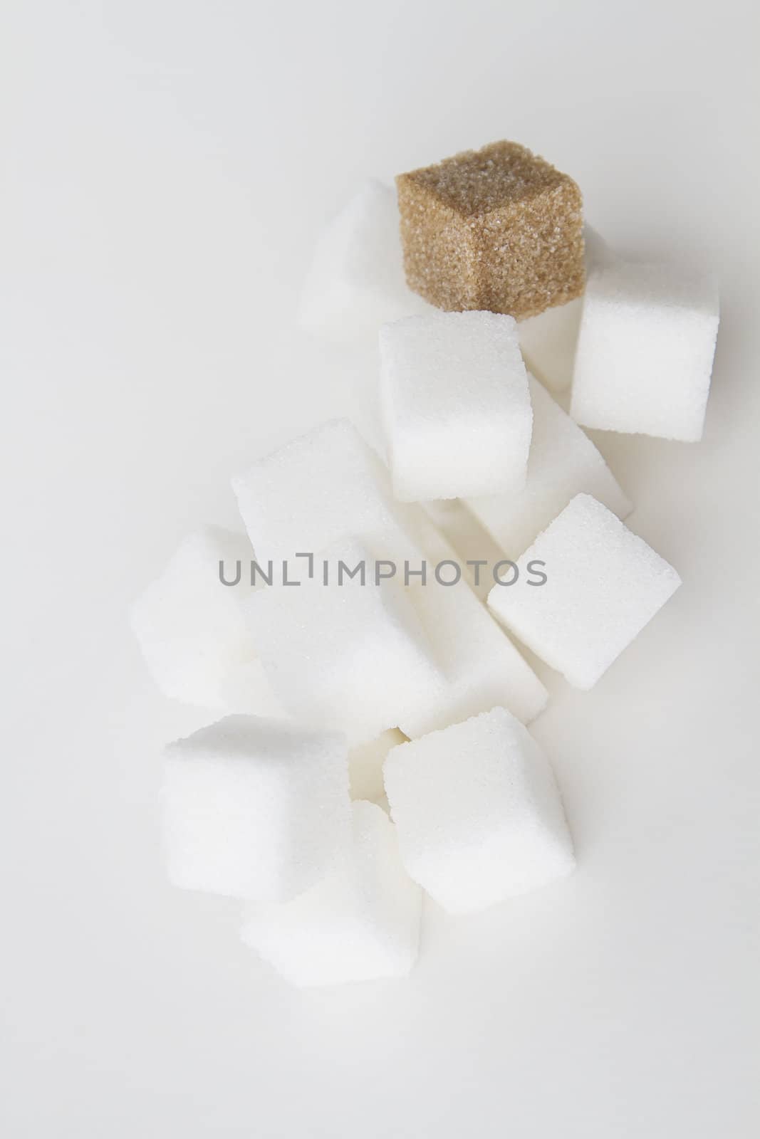 stack of white sugar cube with one brown sugar cube falling down