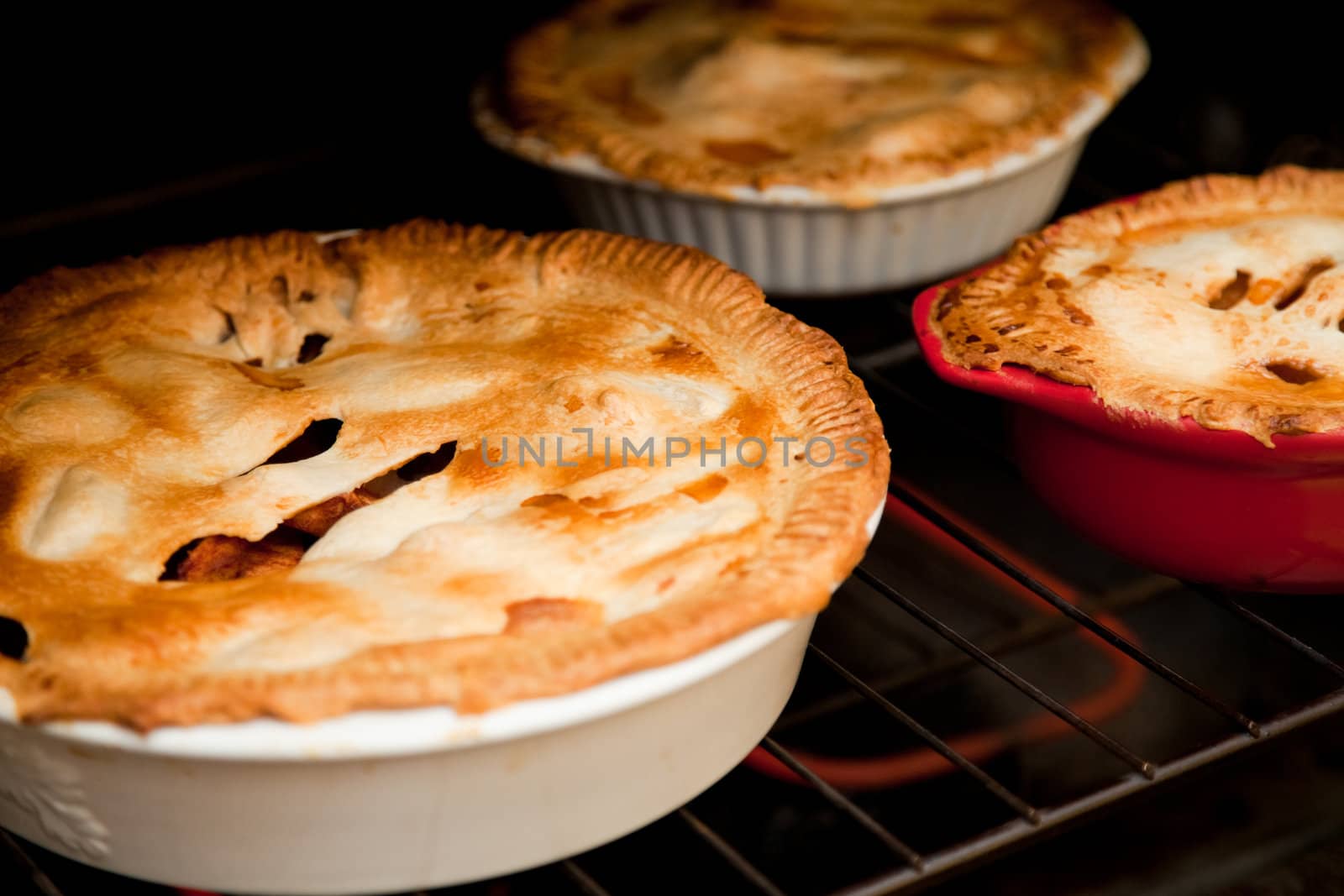 three apple pies cooking in the oven