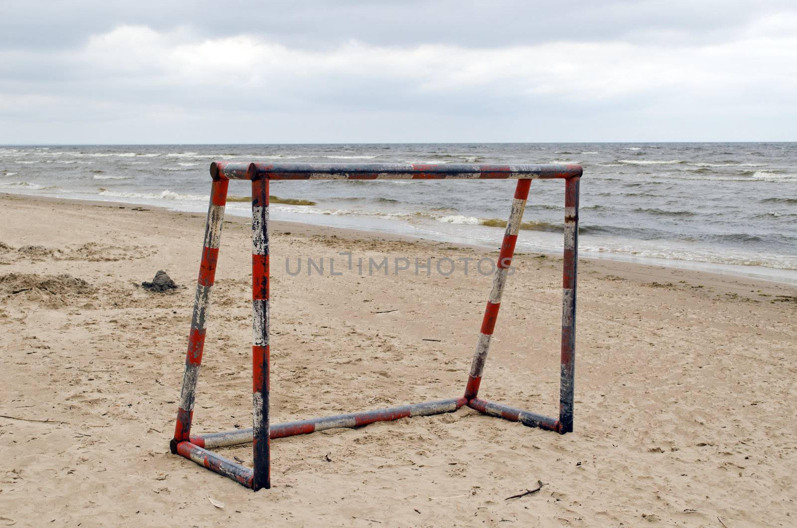 Steel metal football goal gate on sea sand. Active recreation on beach seaside.