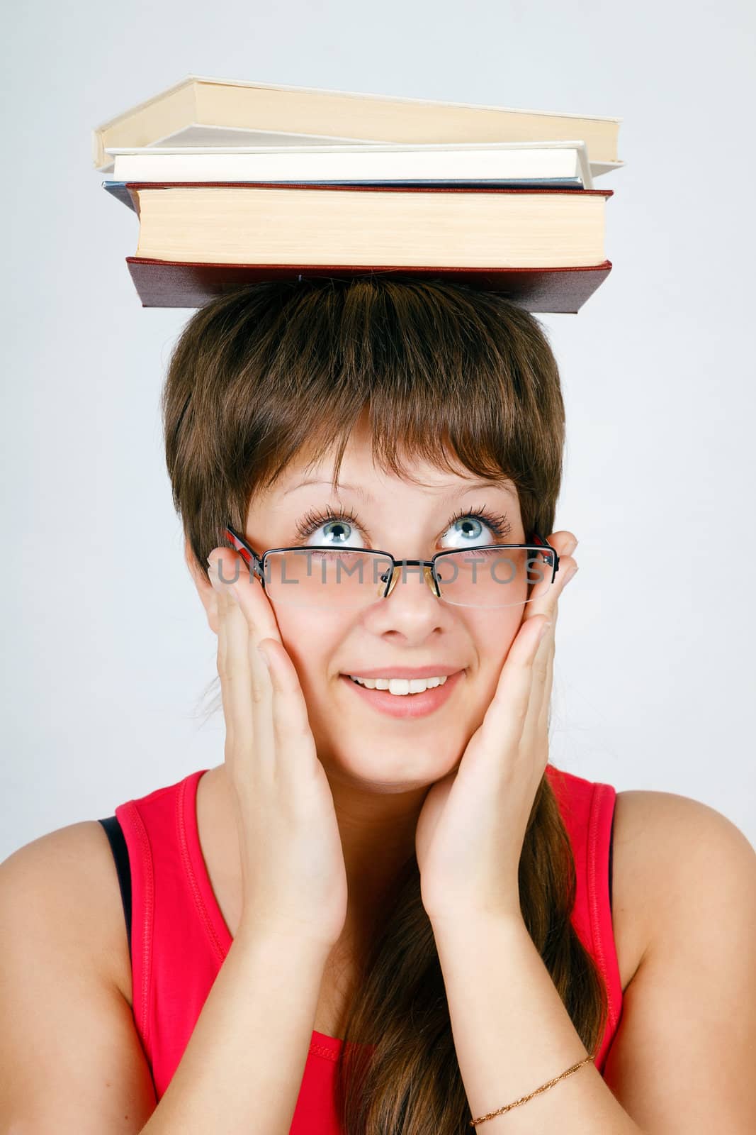 girl in glasses with the books on head on an isolated white background