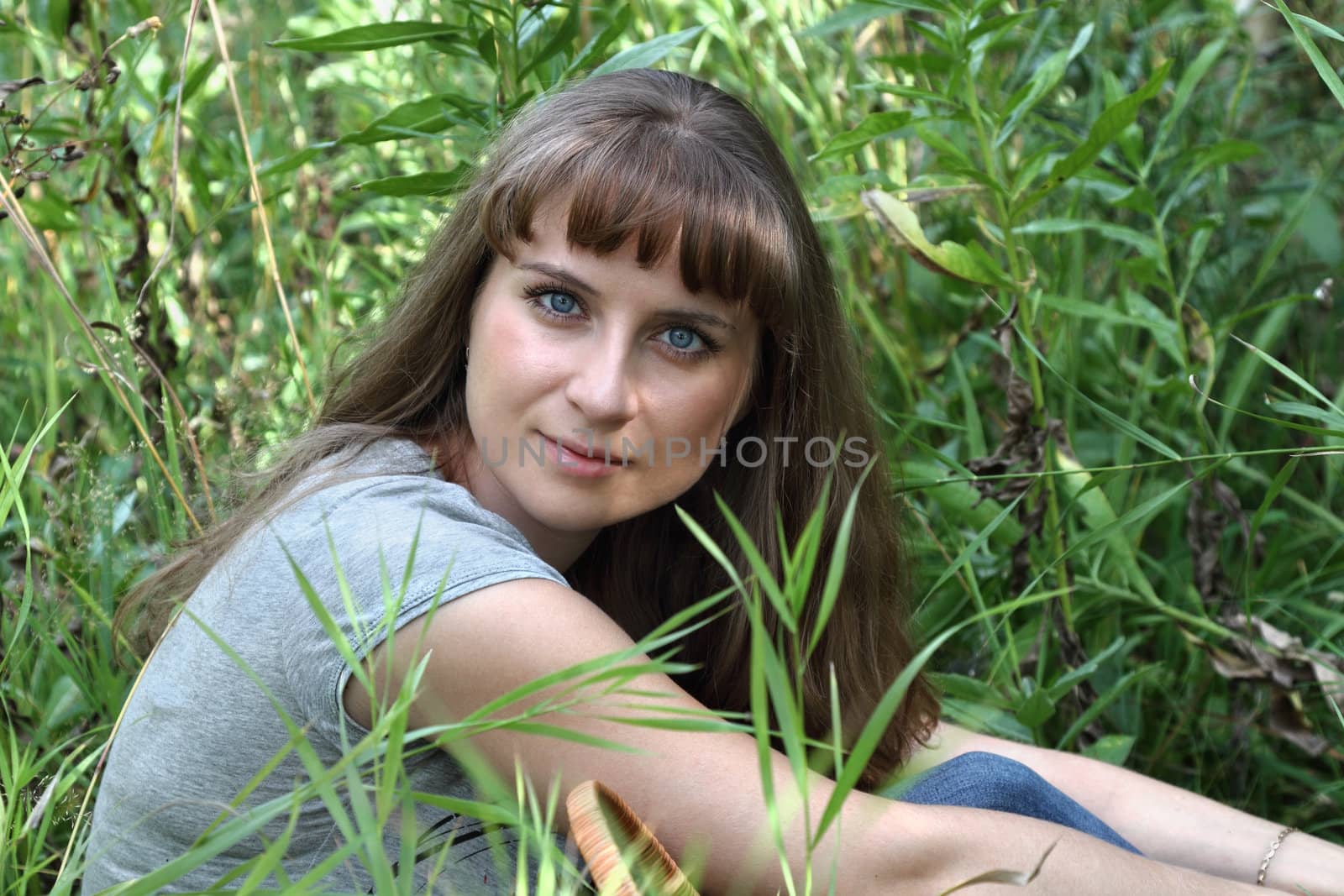 A young girl sitting in the garden in the grass

