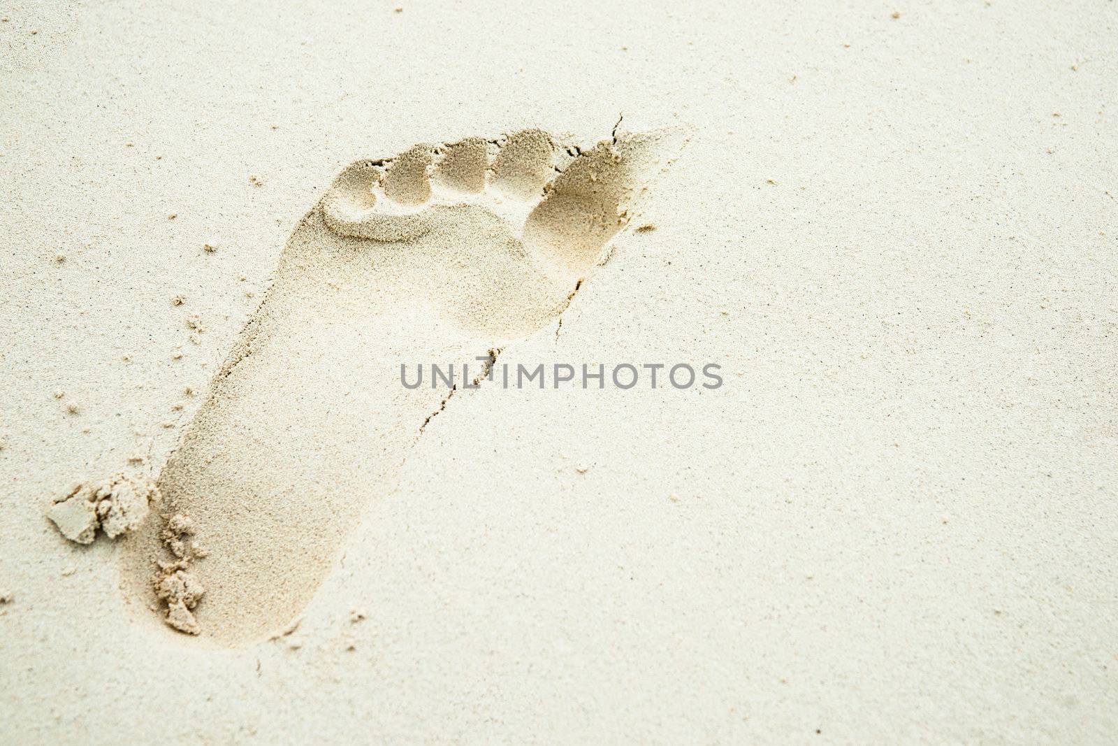 One footprint in white sand.