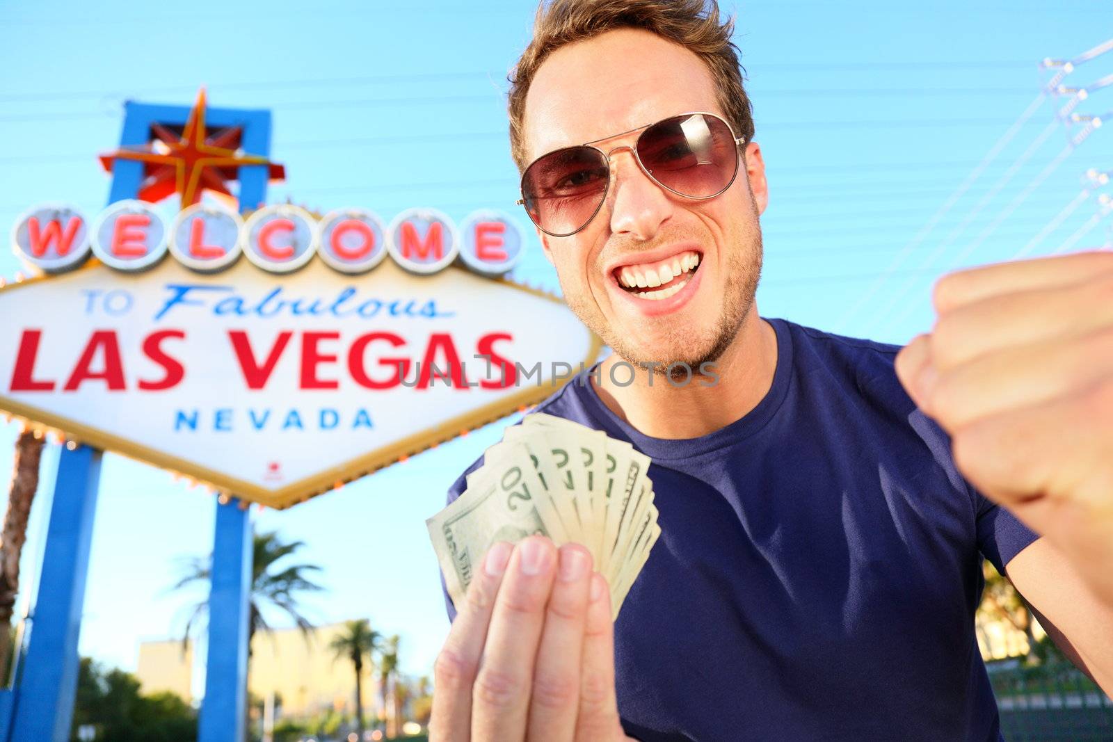 Las Vegas man winning money. Winning gambler standing excited in front of Welcome to Fabulous Las Vegas sign.