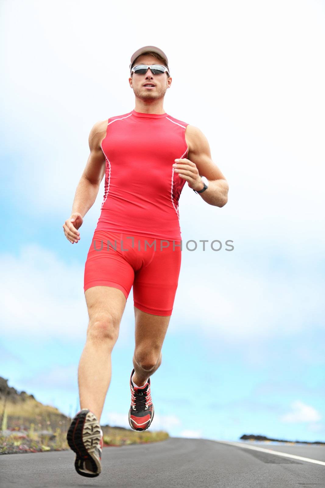 Triathlon running man. Triathlete runner training on Hawaii for ironman. Male athlete running in red compression clothing, shorts and top on volcano on Big Island, Hawaii.