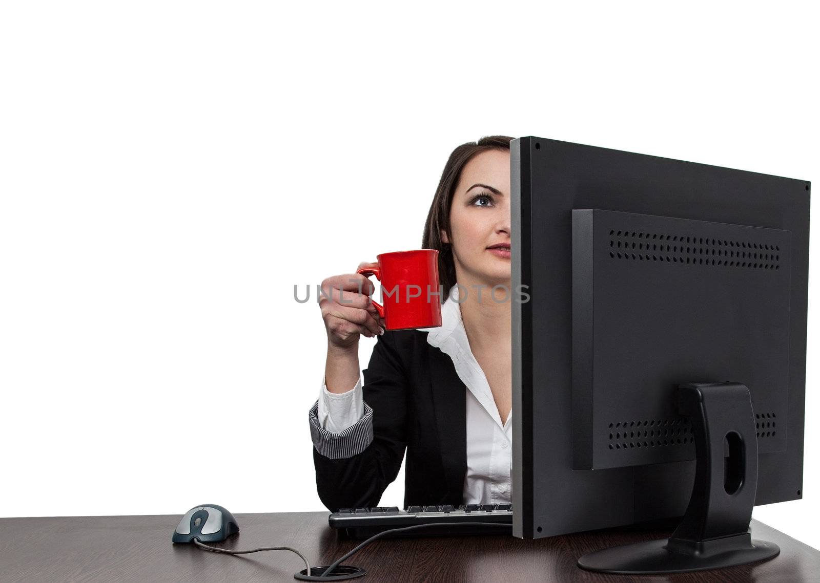 Image of a young businesswoman with a big red cup of coffee in front of her computer at the workplace in the office, isolated against a white background.