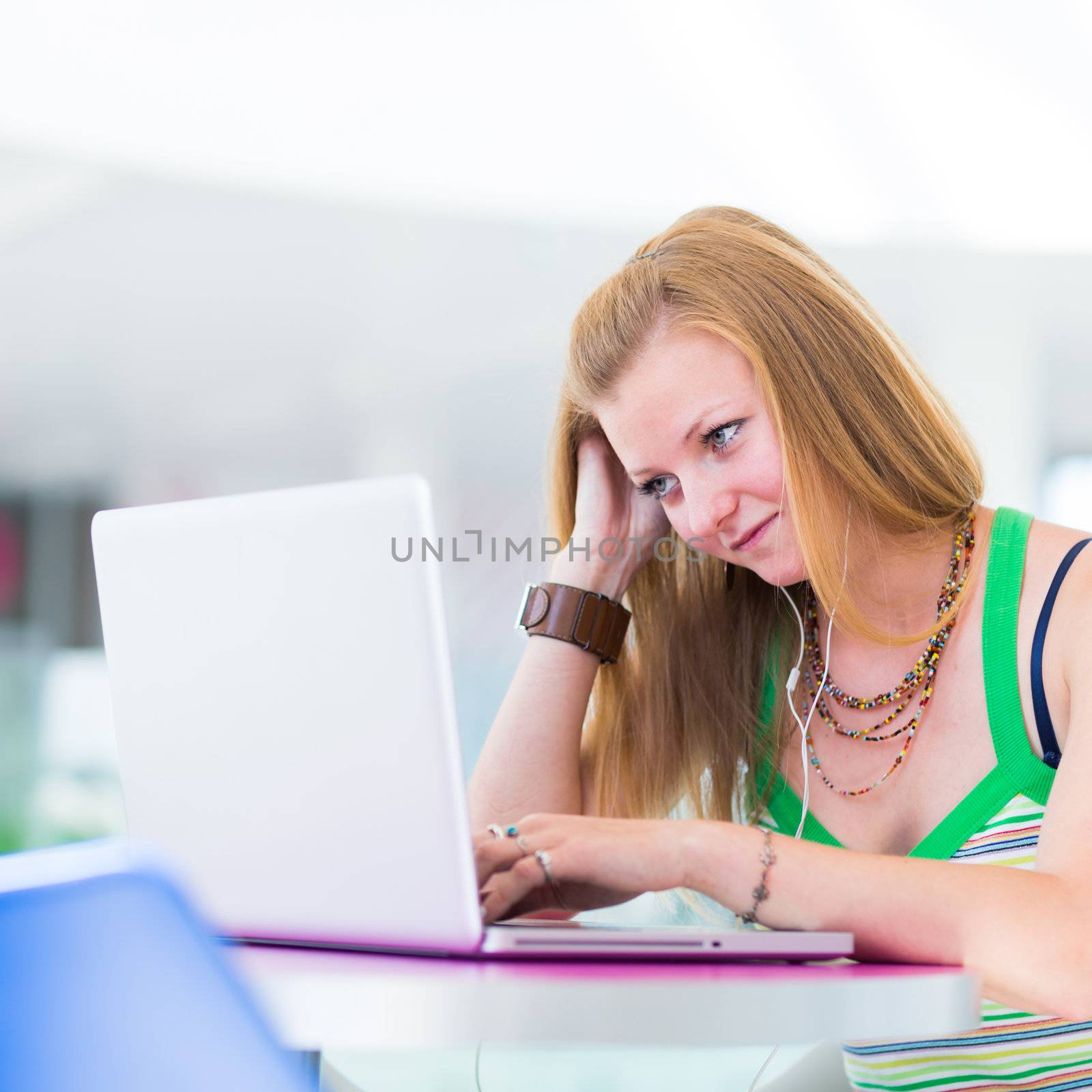 pretty female college student working on her laptop computer on campus, before class (color toned image; shallow DOF)