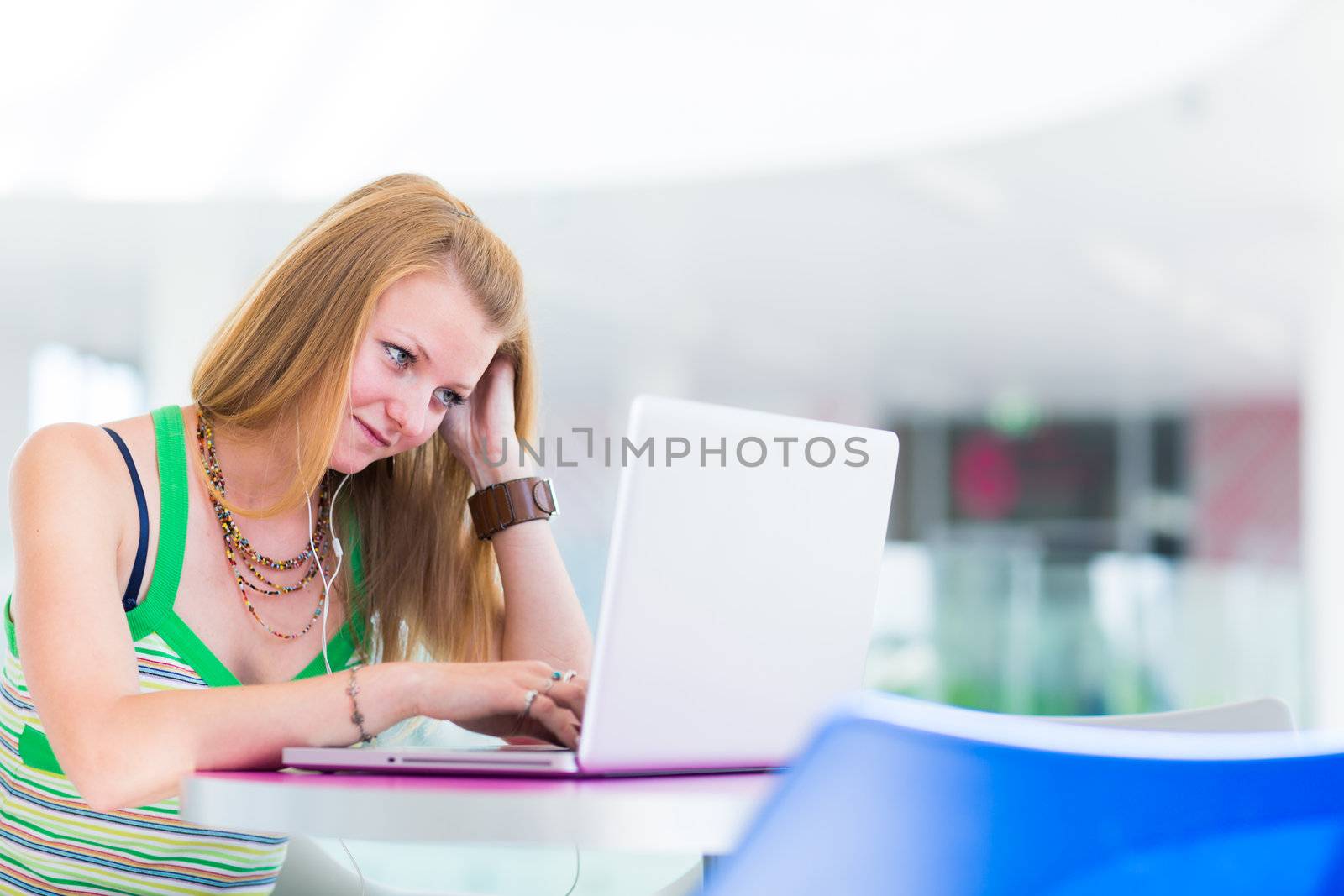 pretty female college student working on her laptop computer on campus, before class (color toned image; shallow DOF)