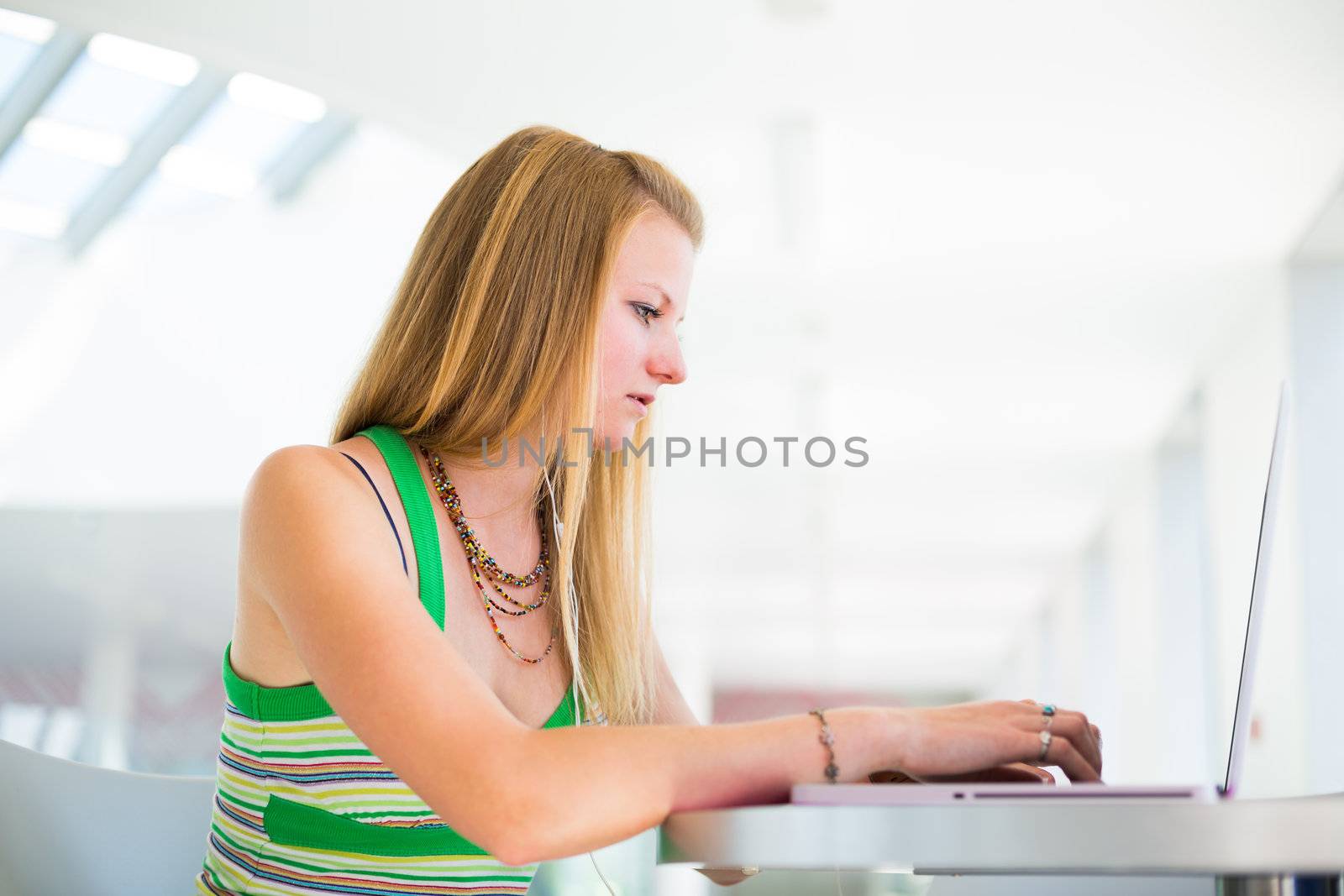 pretty female college student working on her laptop computer on campus, before class (color toned image; shallow DOF)