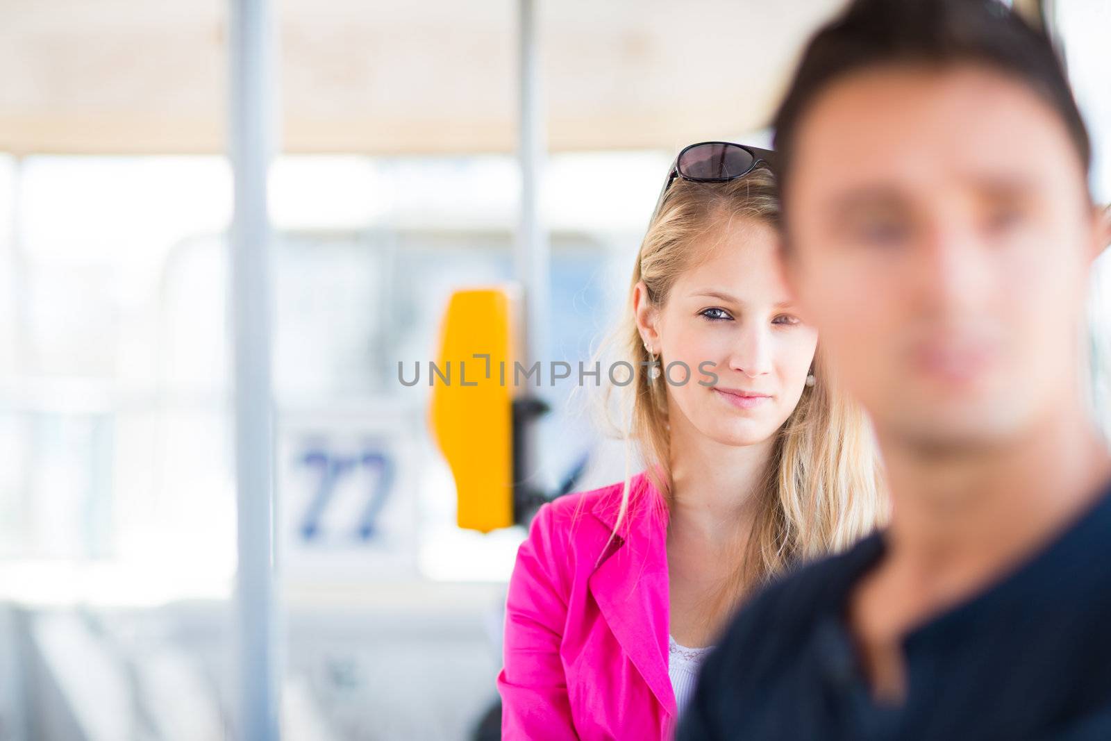 Pretty, young woman on a streetcar/tramway, during her commute to work (color toned image; shallow DOF)