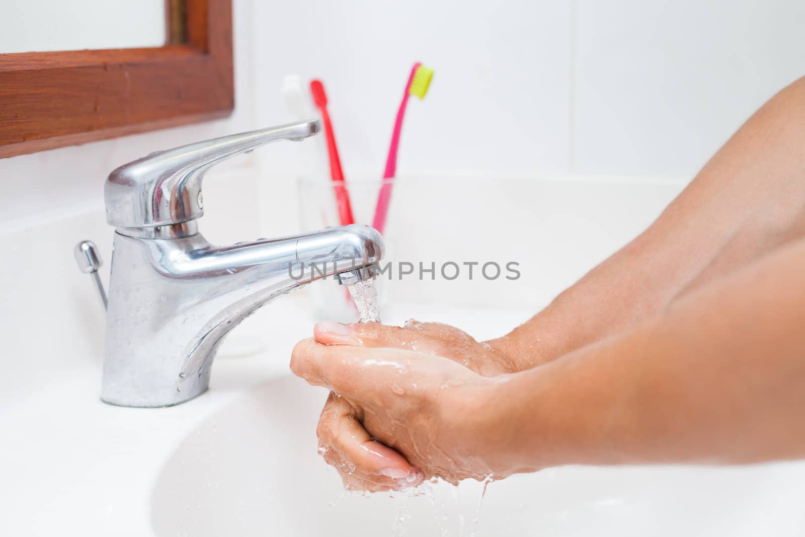 Washing hands under running water in a bathroom (shallow DOF; color toned image)