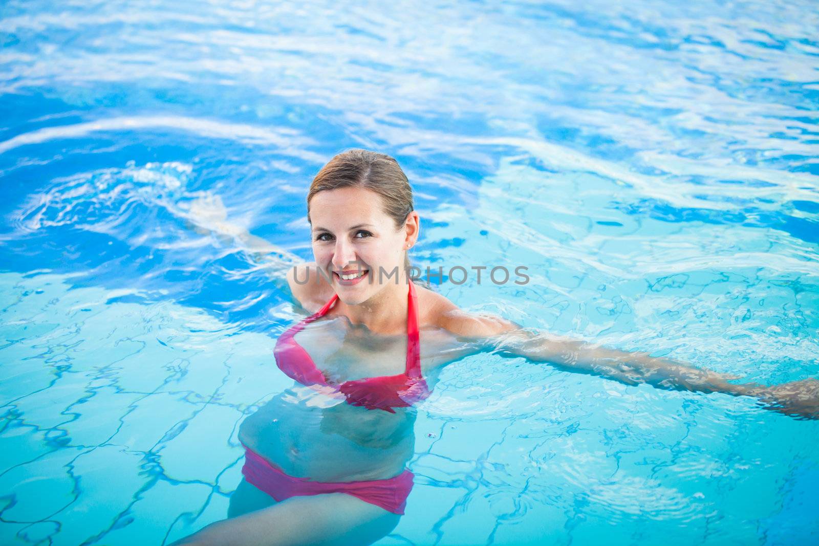 Portrait of a young woman relaxing in a swimming pool by viktor_cap