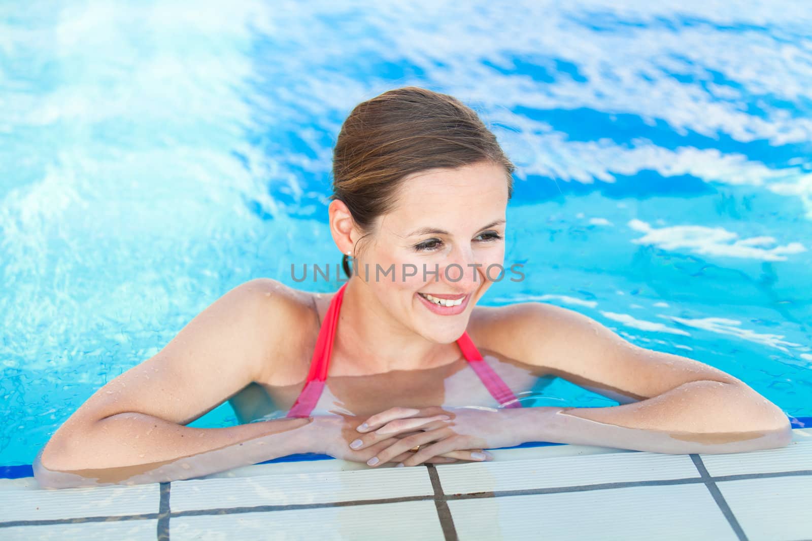 Portrait of a young woman relaxing in a swimming pool by viktor_cap