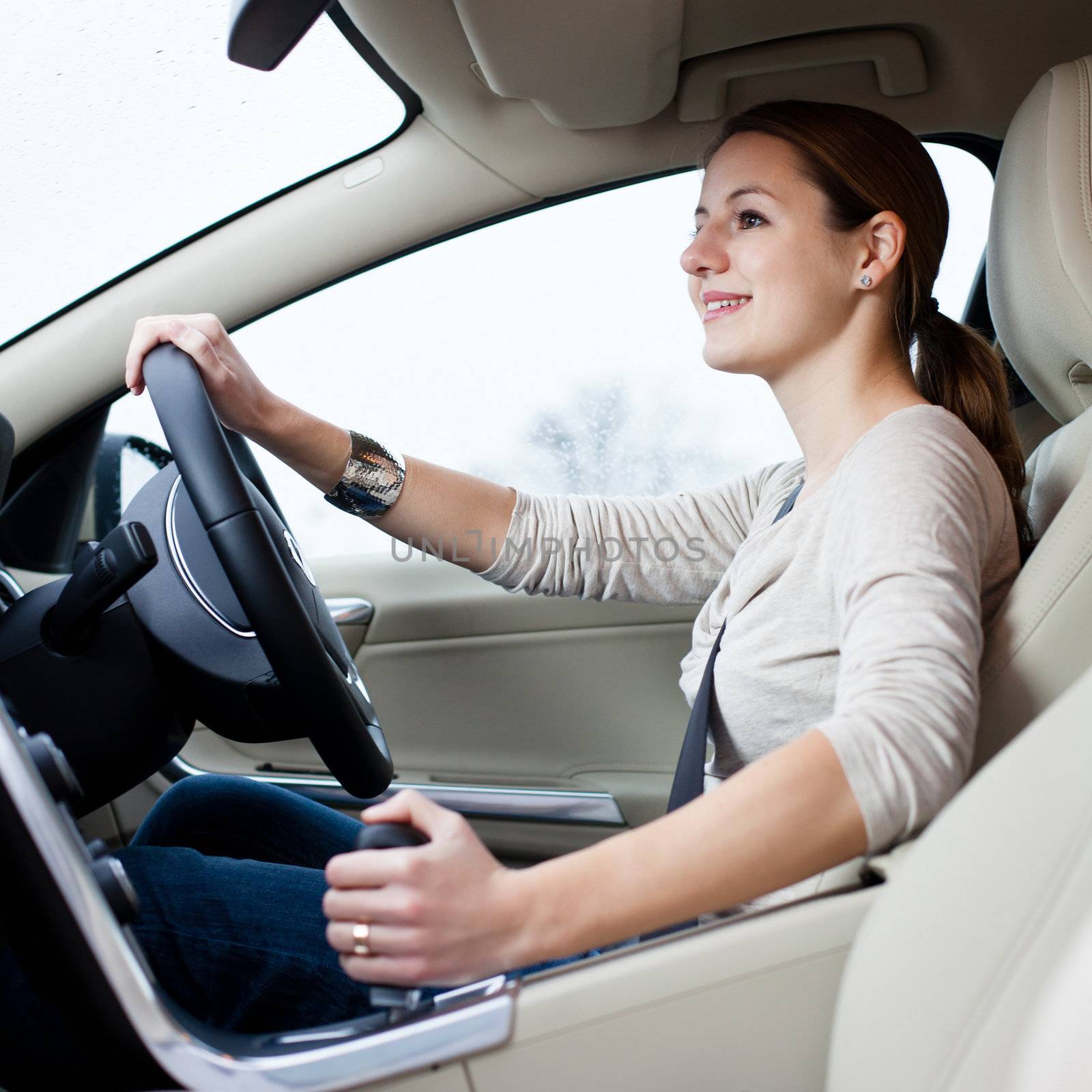 Pretty young woman driving her brand new car shallow DOF; color toned image)