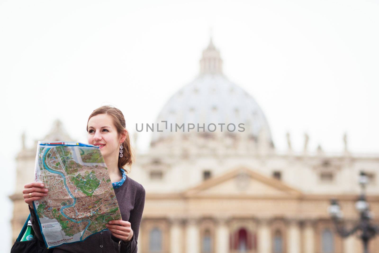 Pretty young female tourist studying a map at St. Peter's square in the Vatican City in Rome