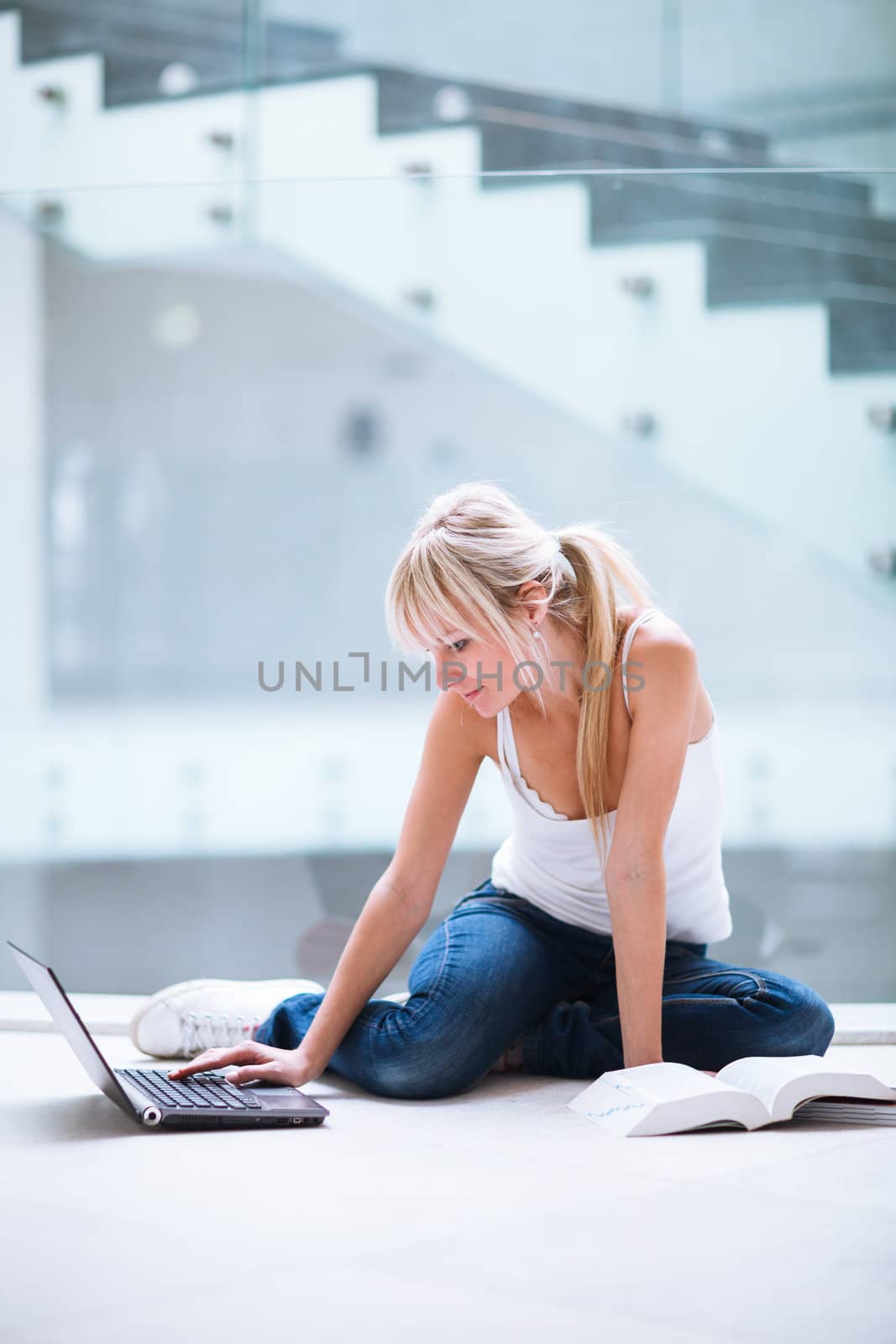 On campus - pretty female student with laptop and books working before class on her assignment/homework  (color toned image)