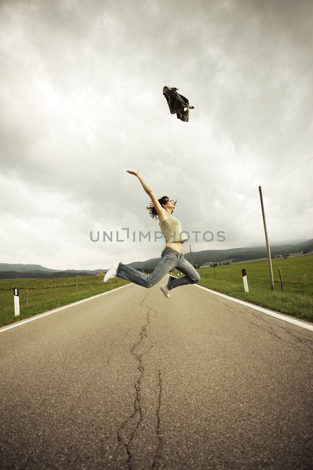 Young woman jumping  on the long empty street.