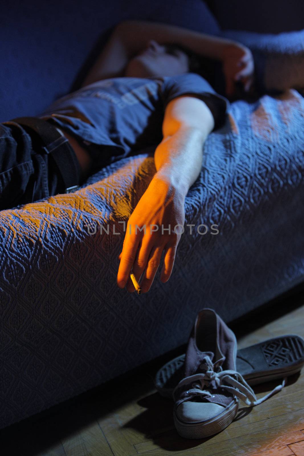 Young man lying on the couch smoking a joint