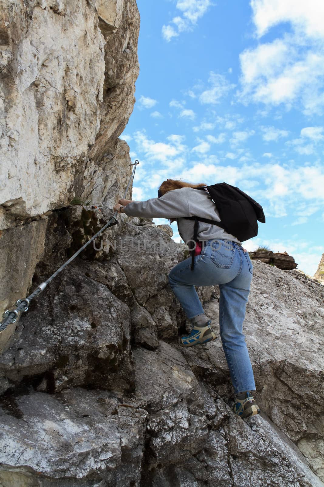 female climber ascending rocks on equipped pathway, Italian Dolomites