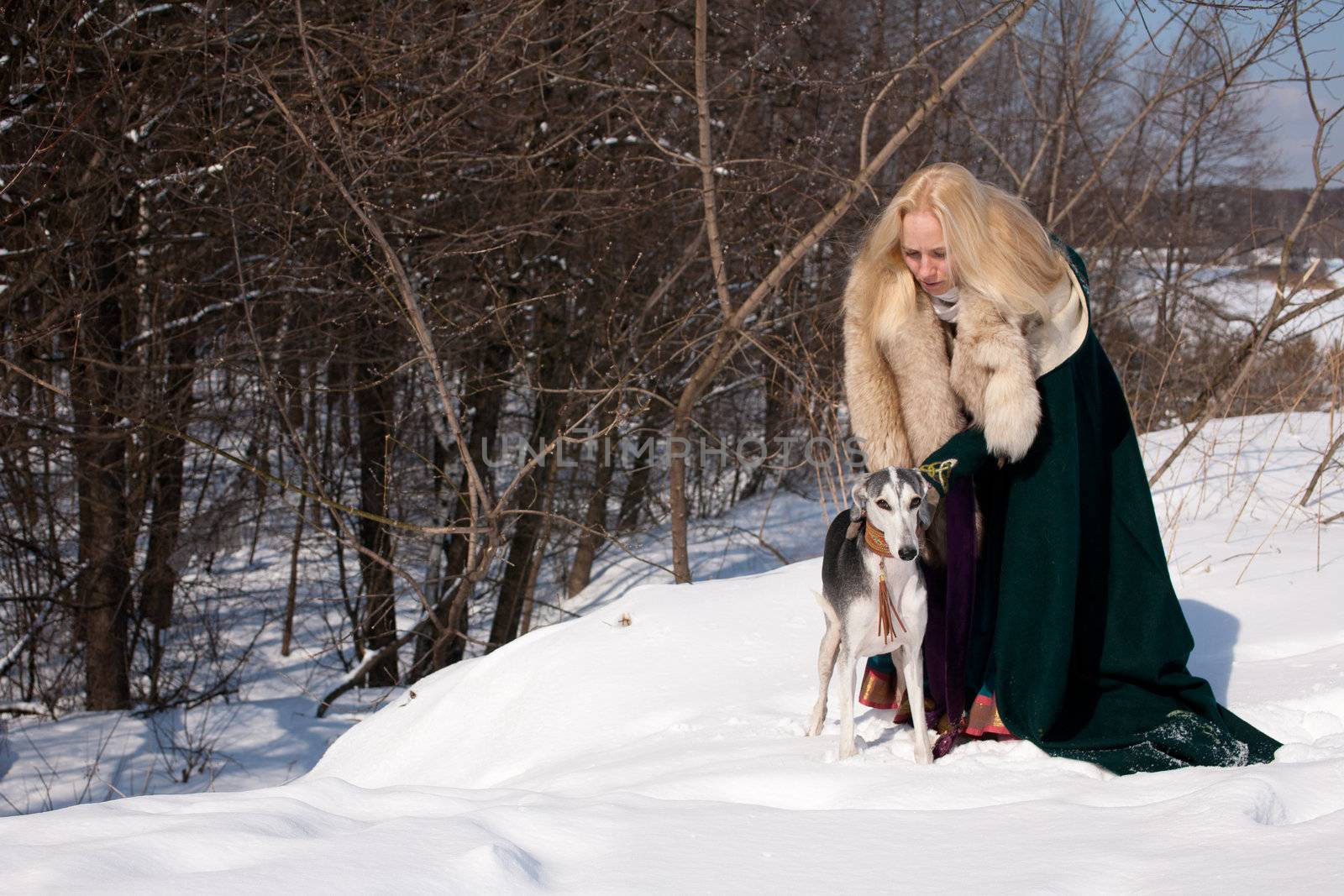 A blonde girl and a grey saluki on snow
