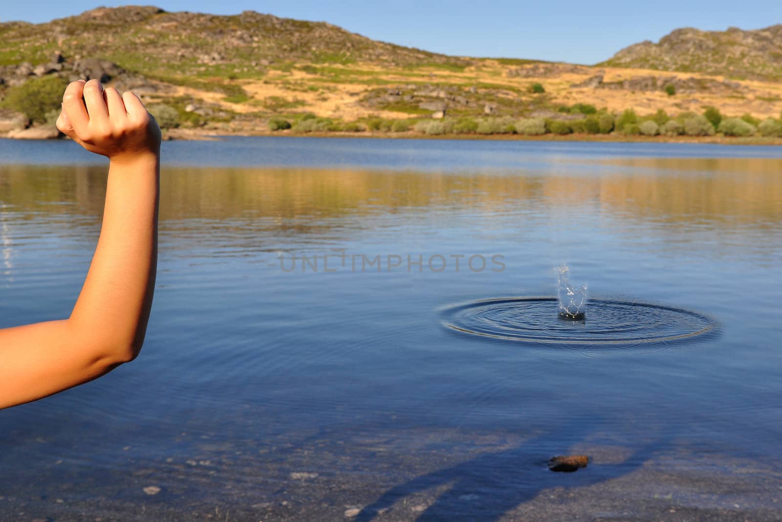 Young woman throwing a stone to a lake