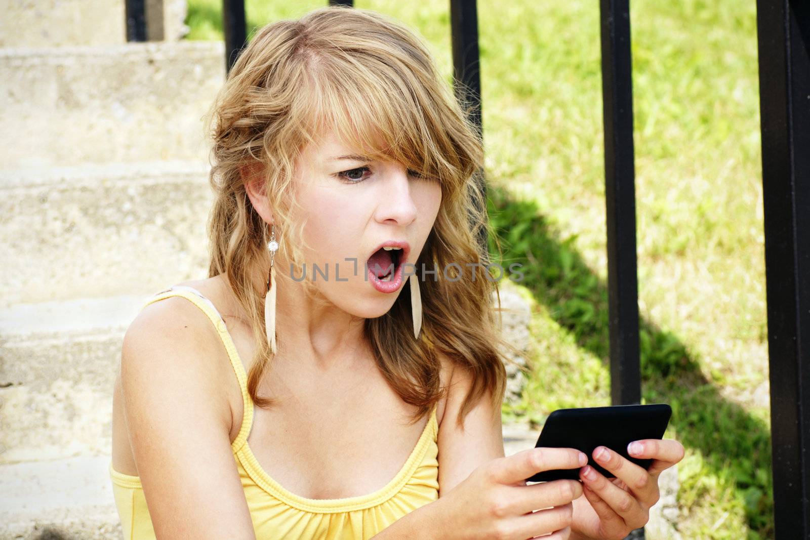 Young woman, teenager girl or student shocked at what she is reading on her cell phone, perfect for online intimidation or bullying at school.