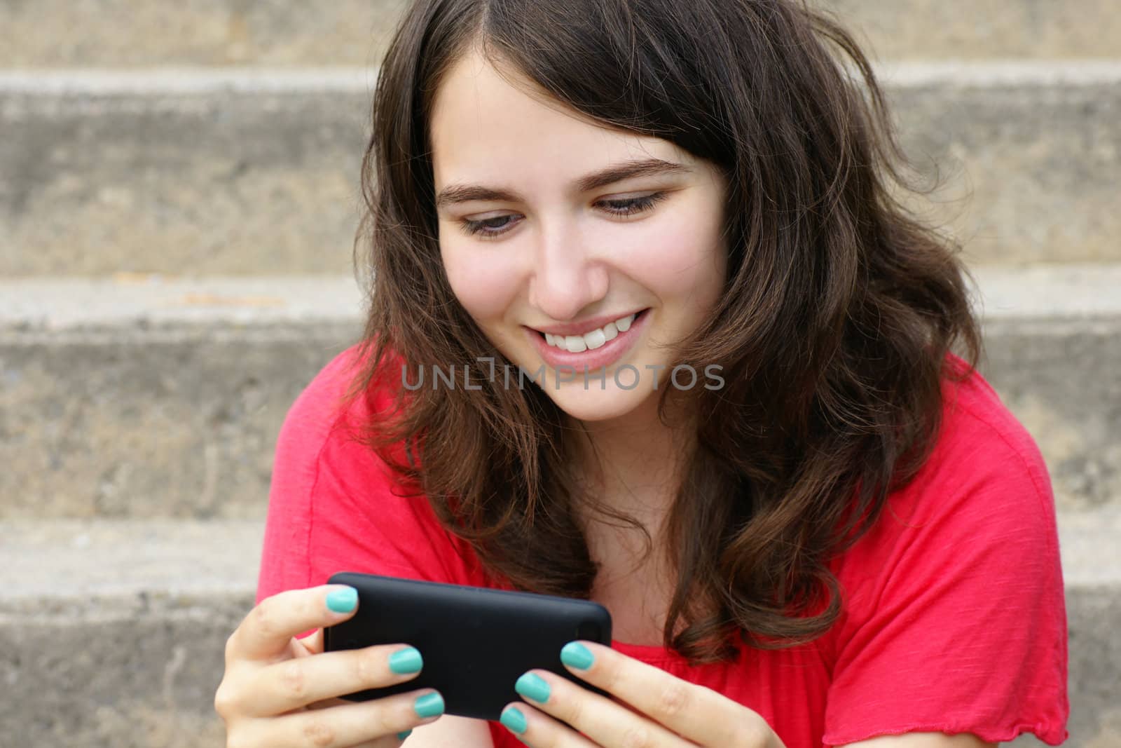 Young woman, teenager girl or student reading text on her cell phone and smiling, perfect for social media, networking or other internet technology.